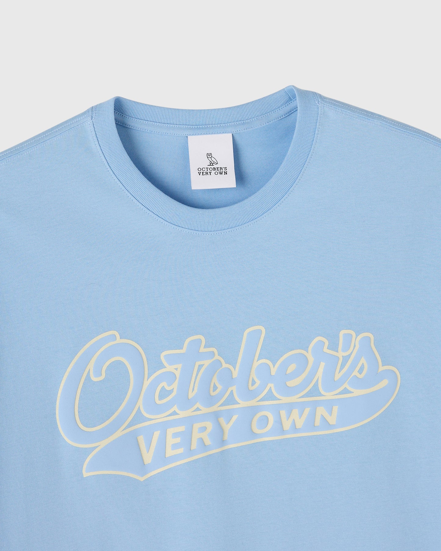 Light blue t-shirt with cream script text reading "Oatbells" and "Very Own" across the chest.