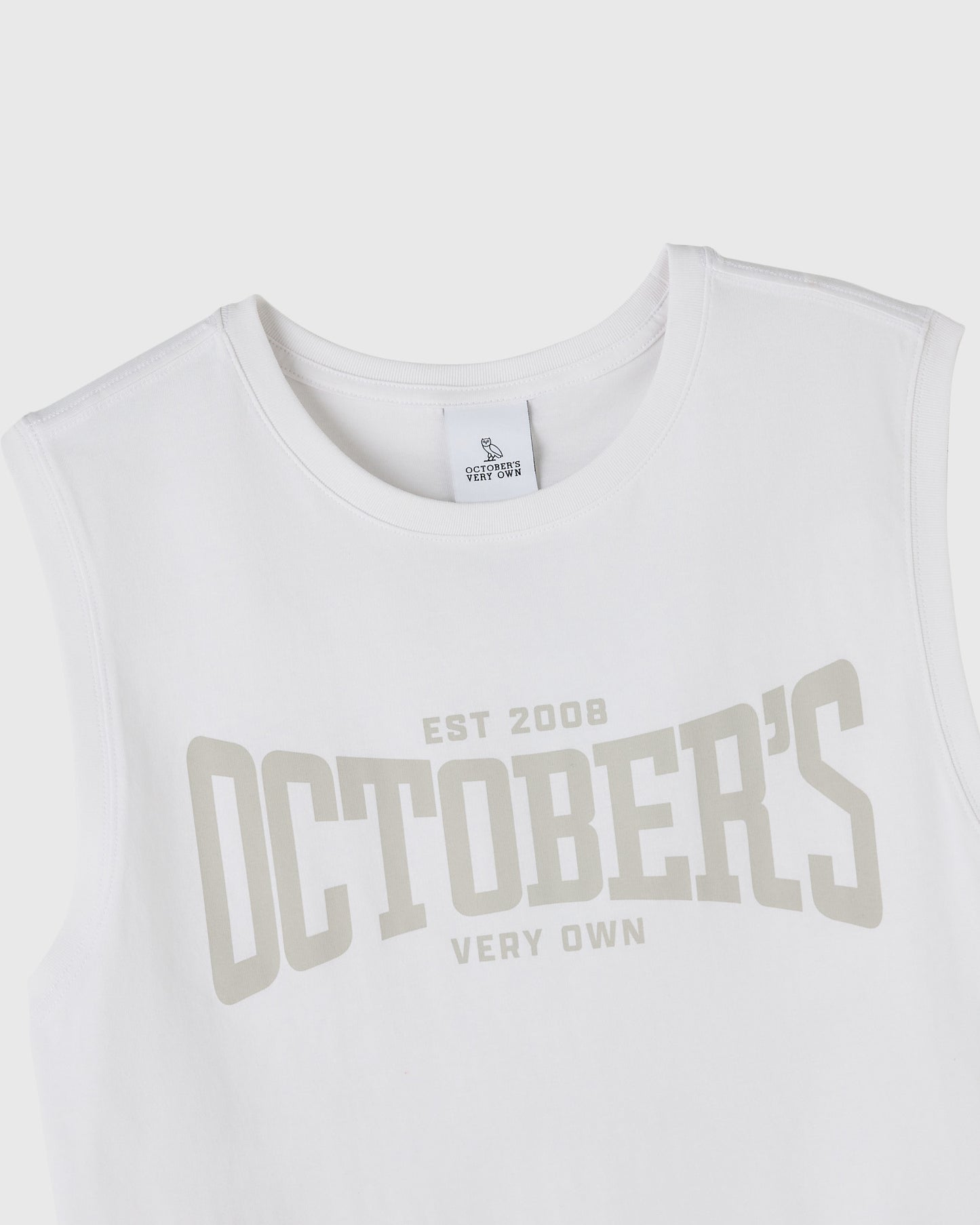 White sleeveless tank top with "EST 2008 OCTOBER'S VERY OWN" text printed in beige across the chest.