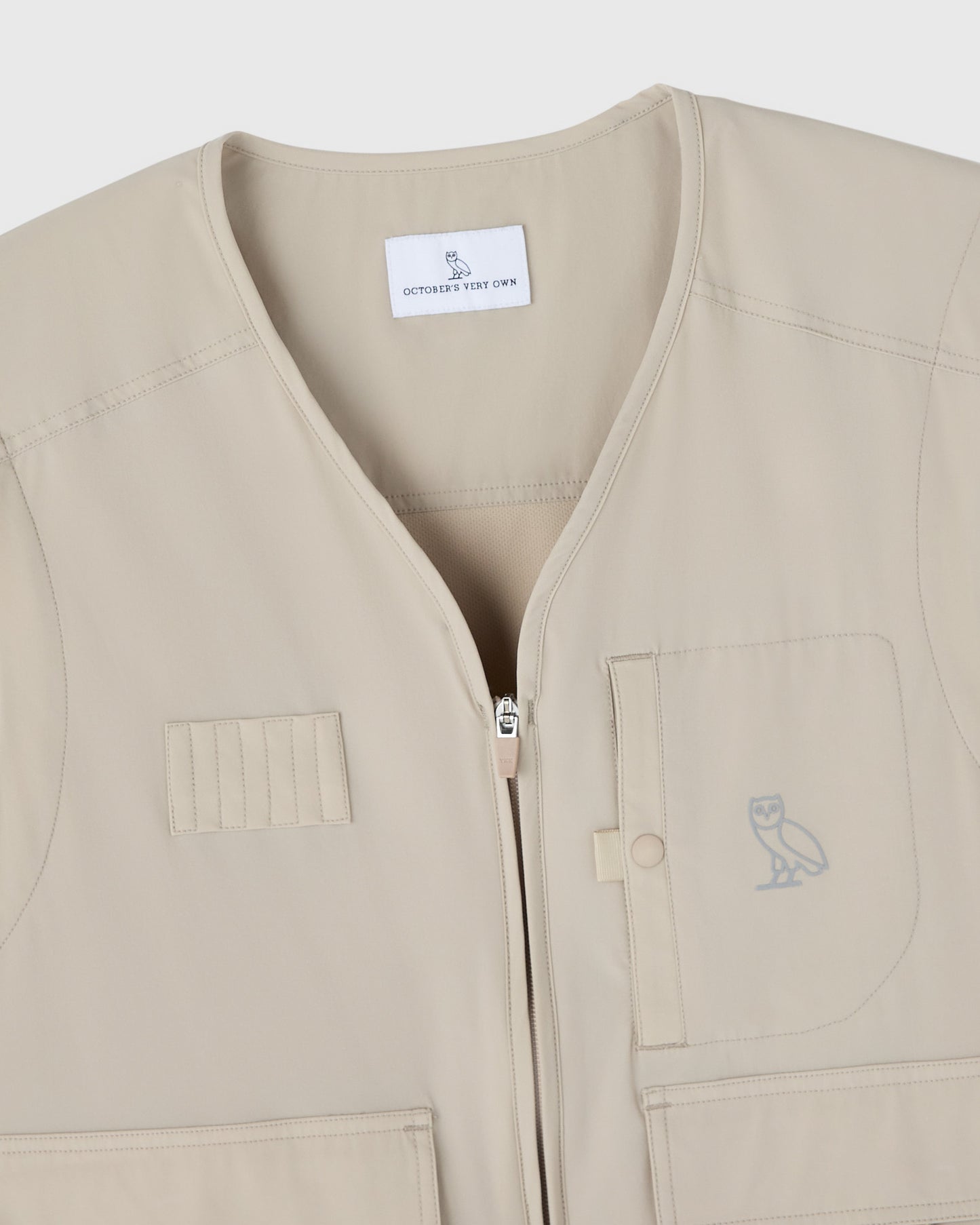 Sandstone-colored nylon golf vest with front zip closure, patch pockets, and OVO owl logo.