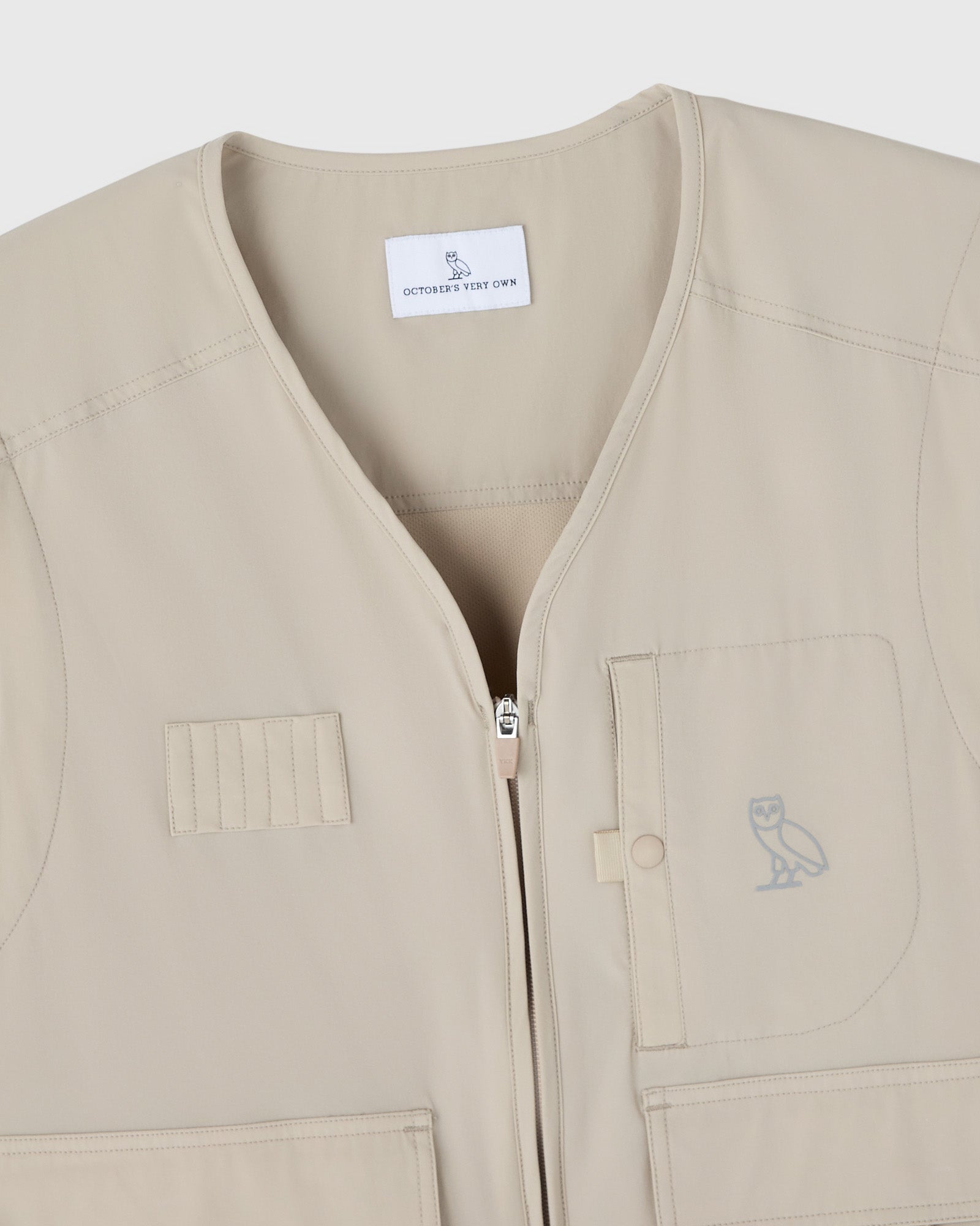 Sandstone-colored nylon golf vest with front zip closure, patch pockets, and OVO owl logo.