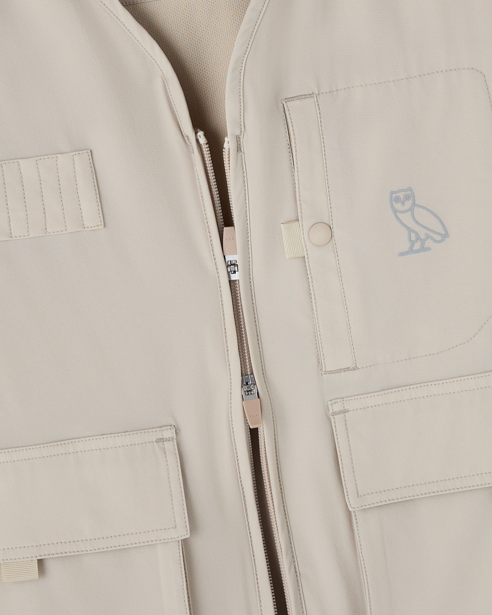 Sandstone stretch nylon golf vest with front zip, multiple patch pockets, and OVO owl logo on chest.