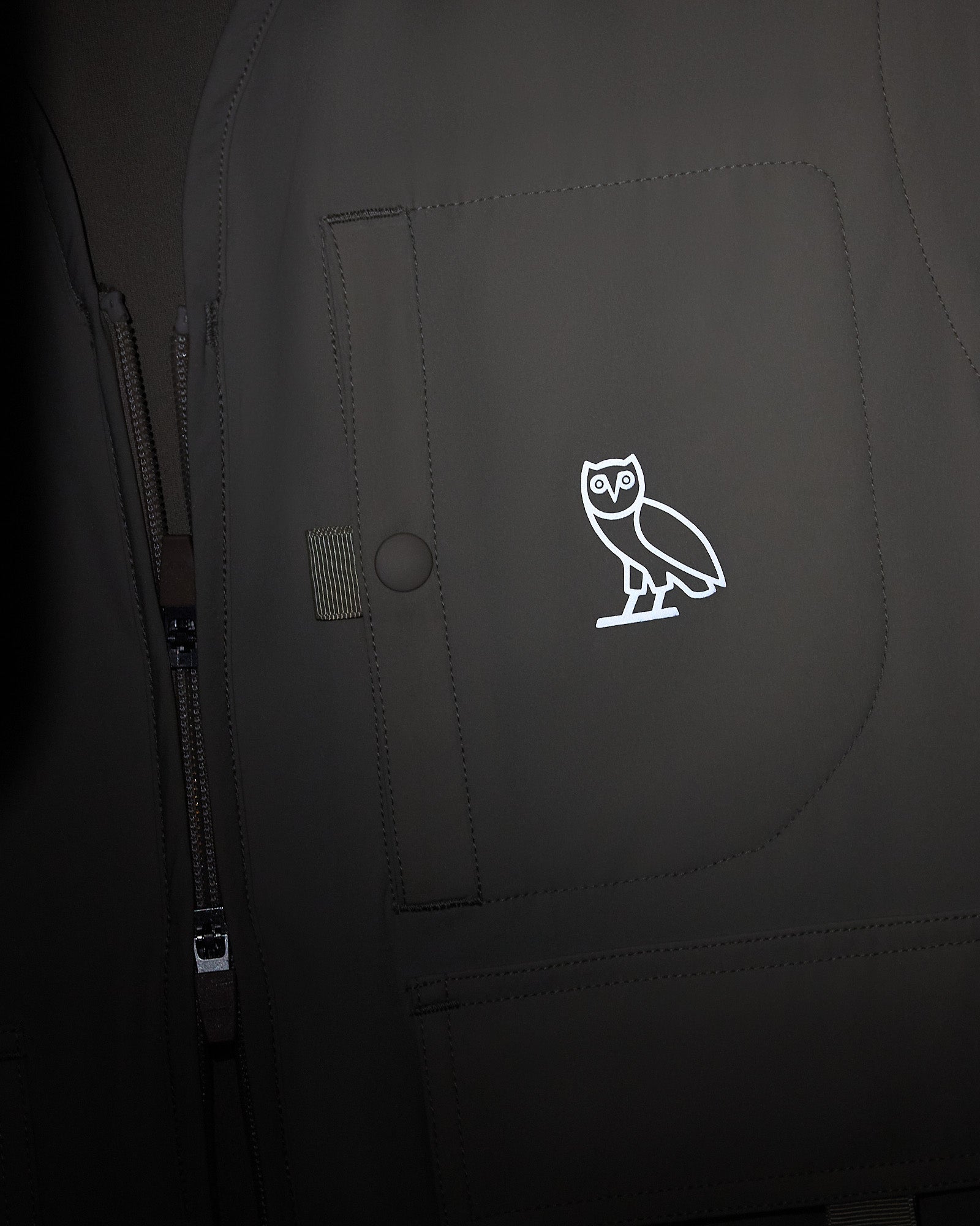 Sandstone stretch nylon vest with full-length zipper, chest pockets, and white owl logo on front.