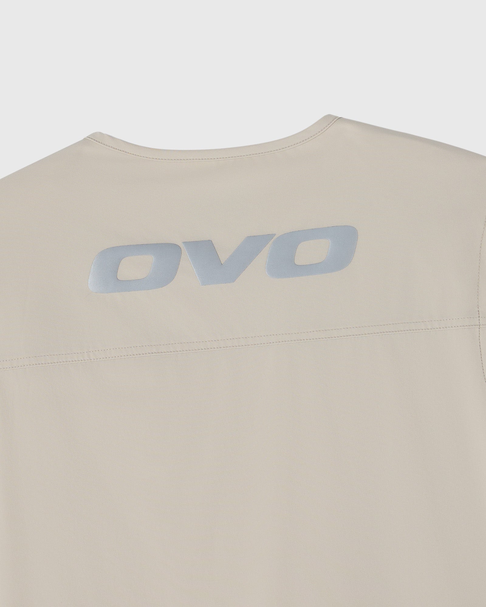 Sandstone-colored sleeveless vest with OVO logo printed on back.