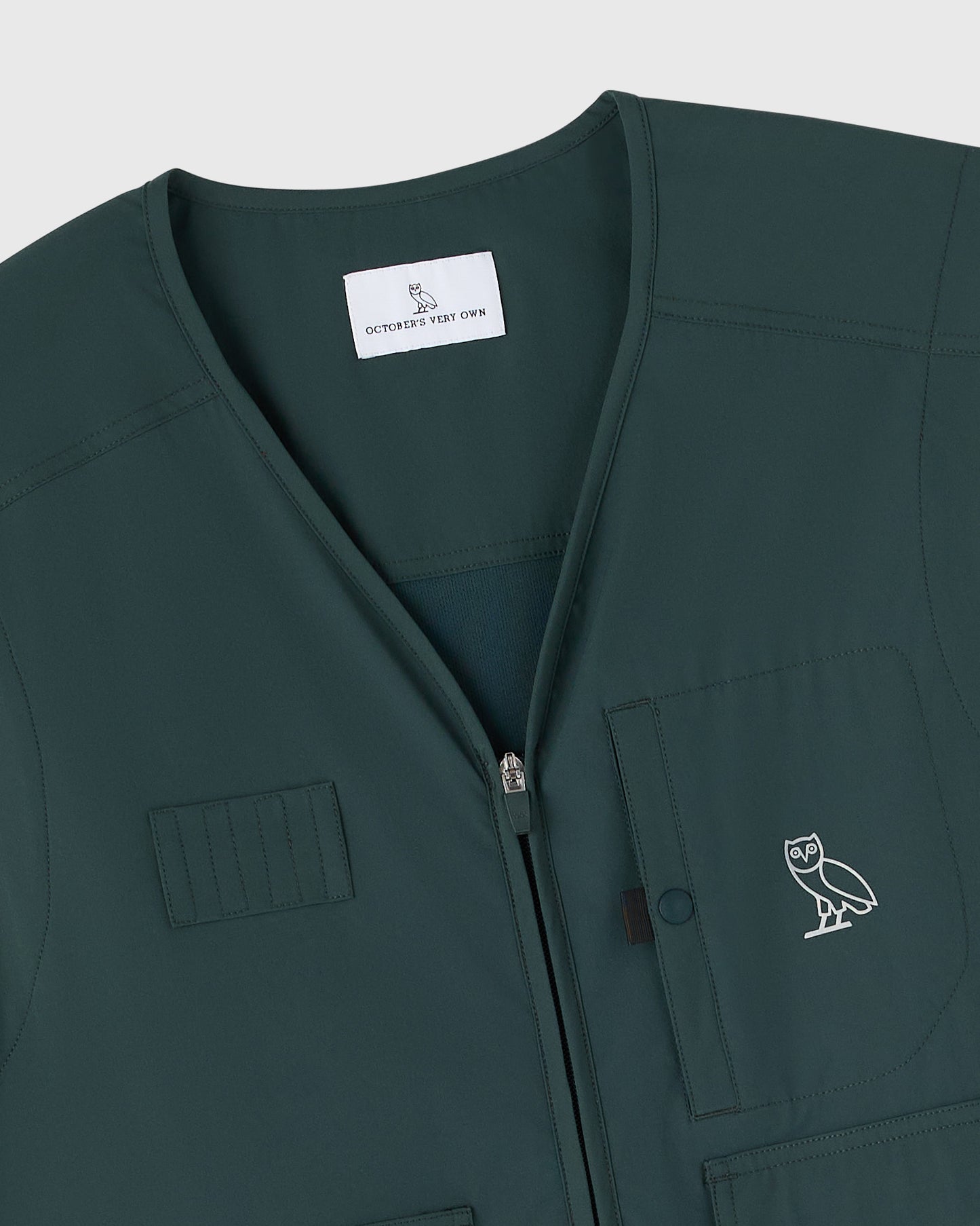 Midnight green stretch nylon golf vest with front zip closure, chest pockets, and OVO owl logo embroidered on chest.