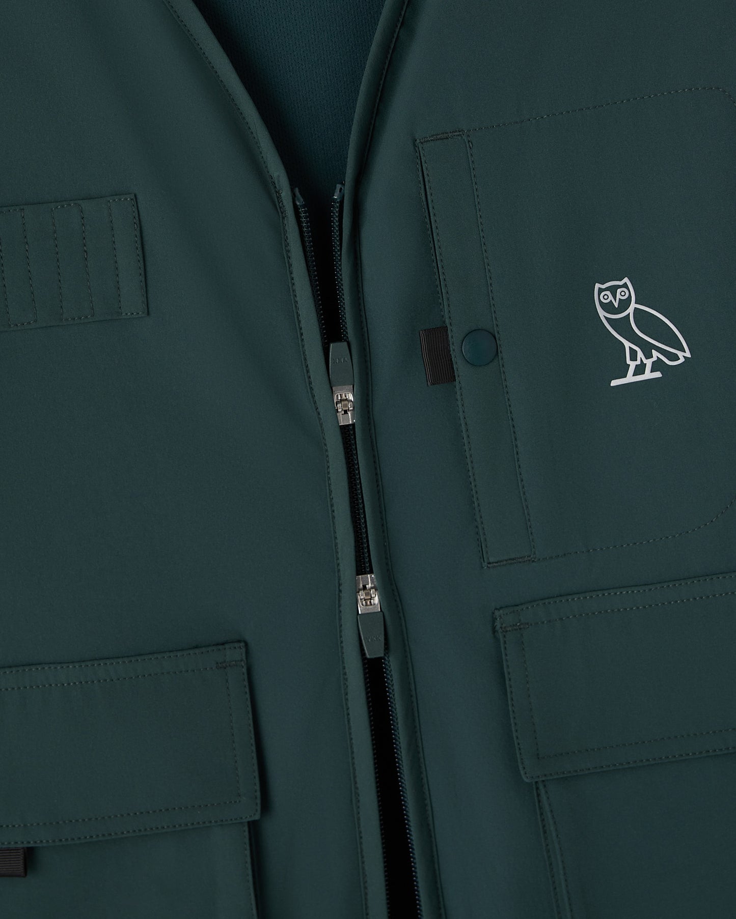 Midnight green stretch nylon vest with front zip, multiple pockets, and OVO owl logo embroidered on chest.