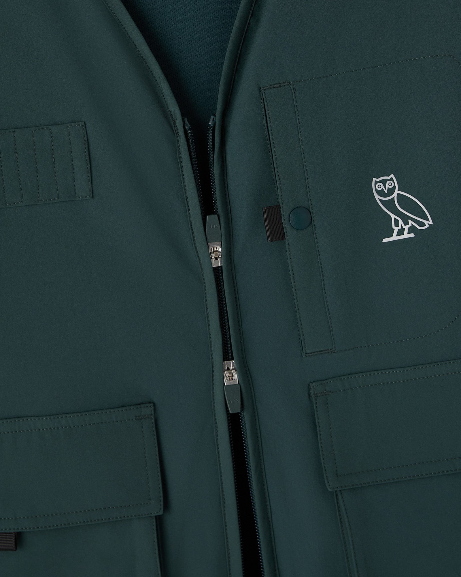 Midnight green stretch nylon vest with front zip, multiple pockets, and OVO owl logo embroidered on chest.