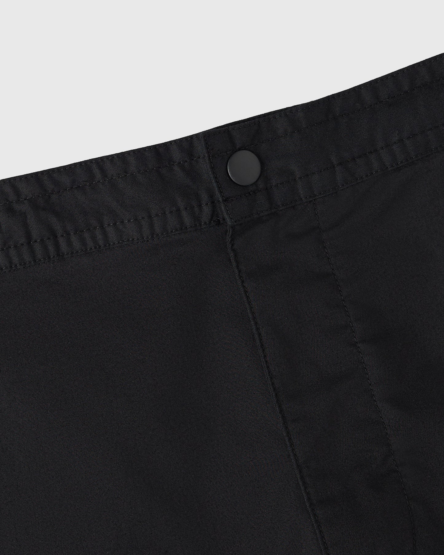 Black camp short with button closure and vertical seam detailing on front.