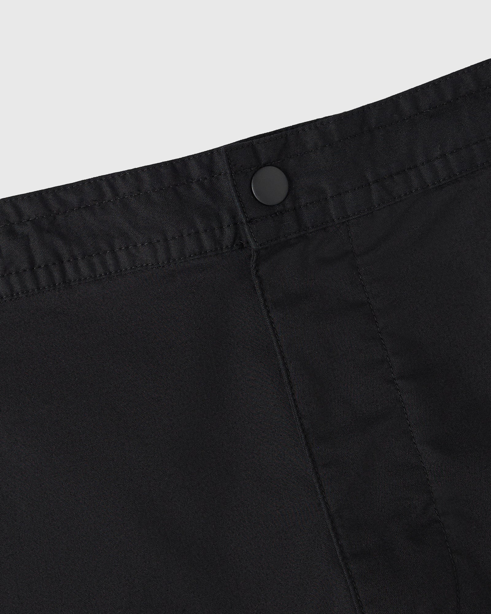 Black camp short with button closure and vertical seam detailing on front.