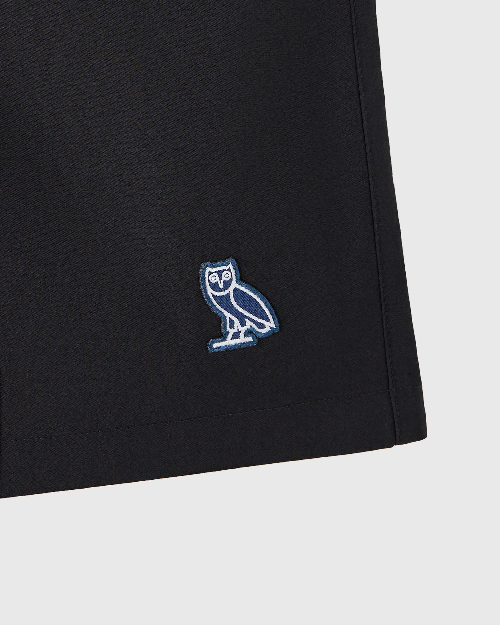 Black shorts with blue and white owl embroidered logo on thigh.