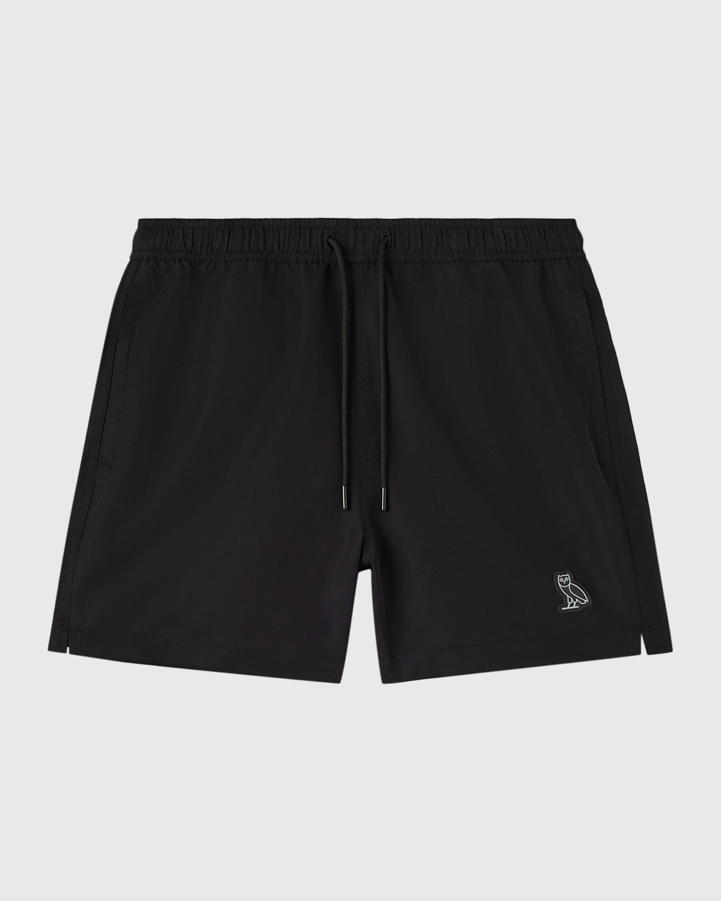 Black swim shorts with elastic waistband, drawstring, side pockets, and small embroidered owl logo on leg.