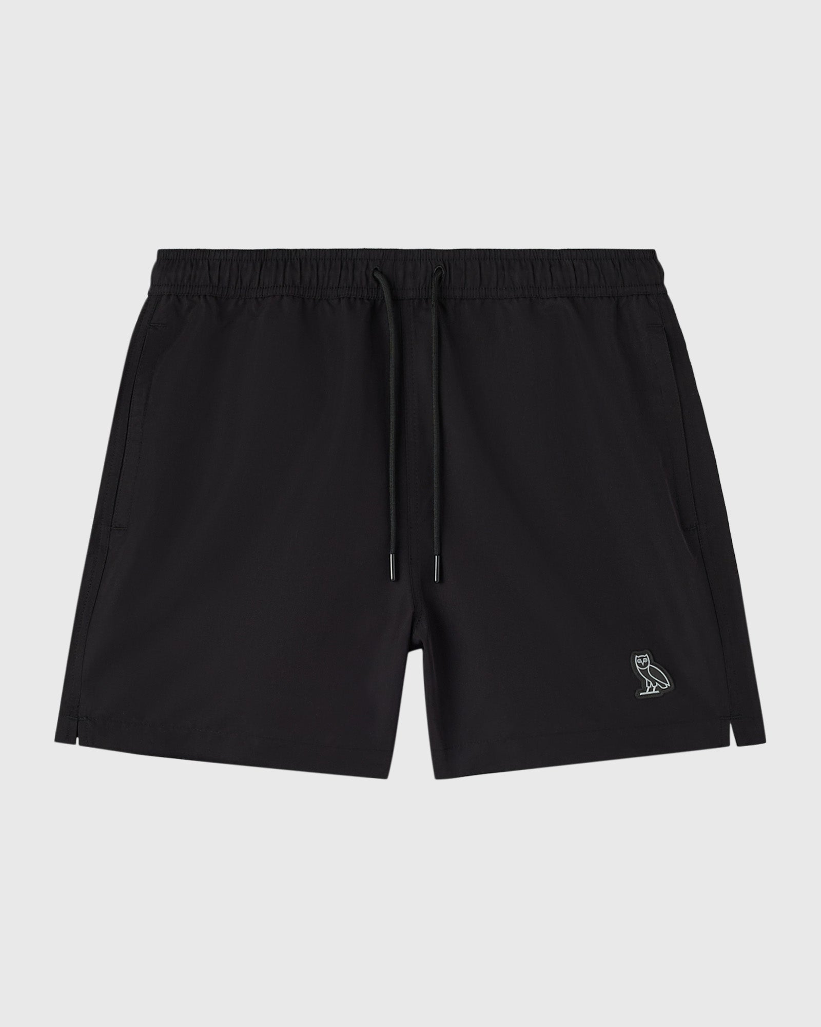Black swim shorts with elastic waistband, drawstring, side pockets, and small embroidered owl logo on leg.