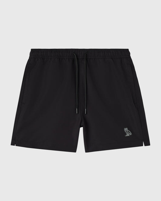 Black swim shorts with elastic waistband, drawstring, side pockets, and small embroidered owl logo on leg.