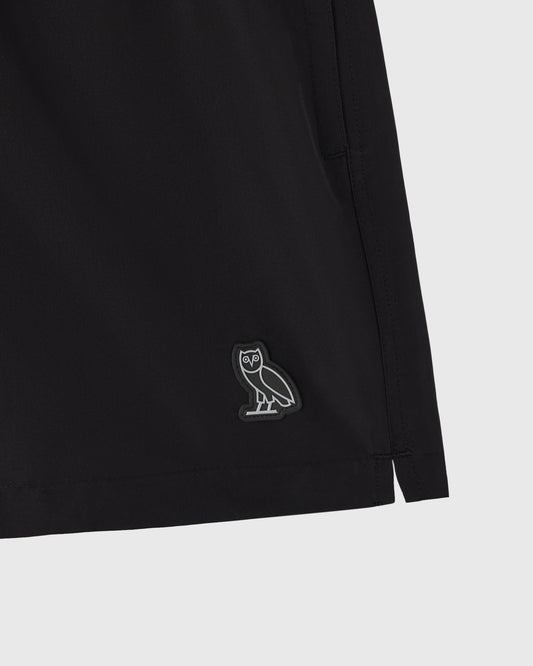 Black swim short with small owl emblem on leg.