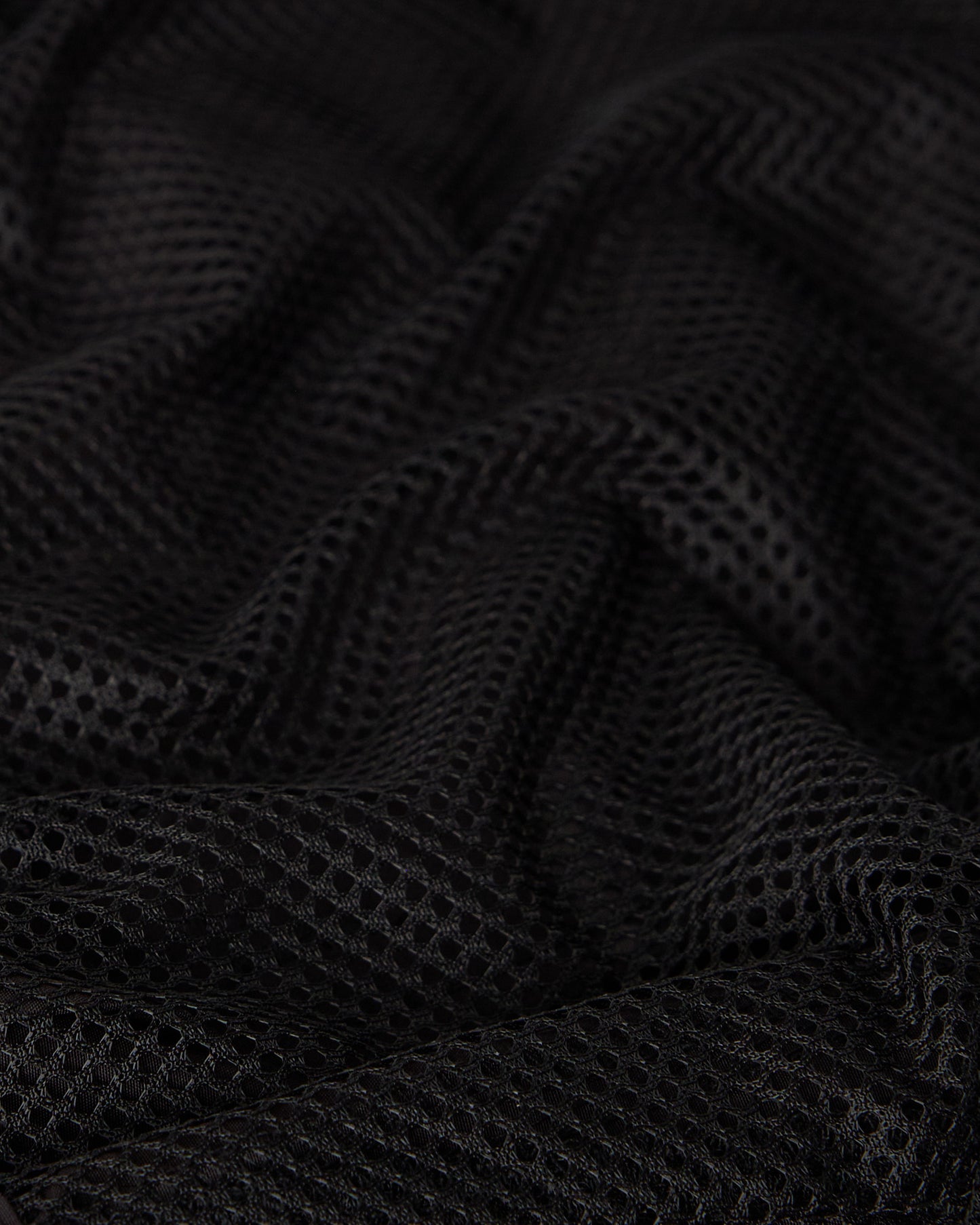 Black swim short with textured mesh fabric and draped folds.