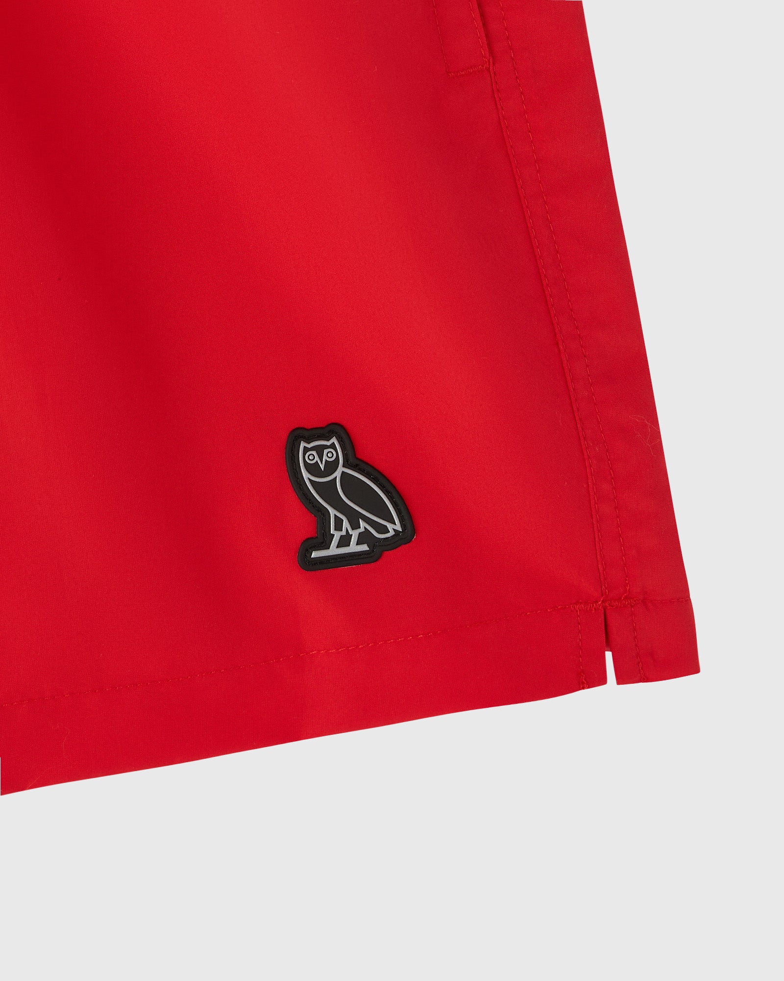 Red swim short with black owl embroidered logo on front.