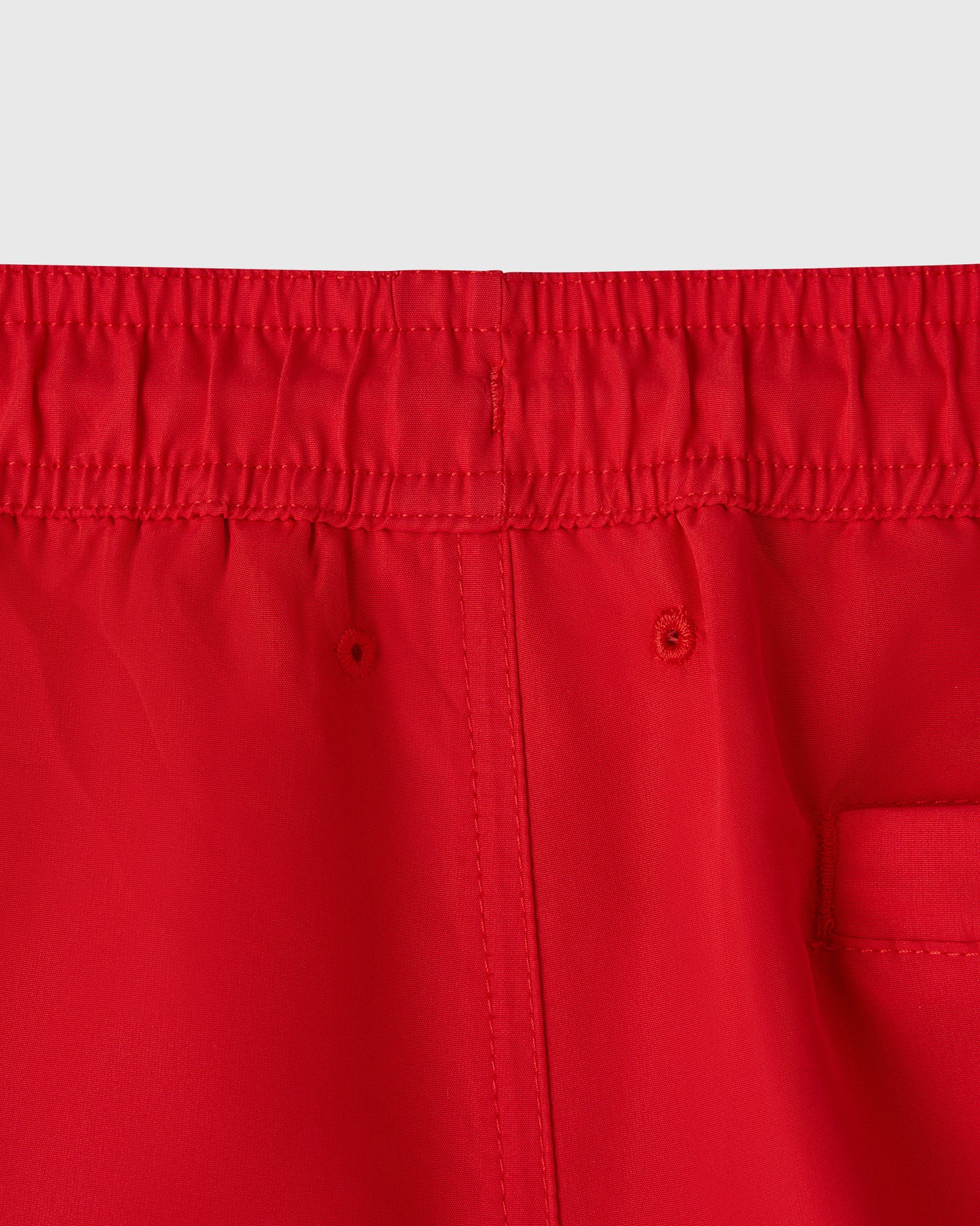Red swim shorts with elastic waistband, center front seam, and side pocket detail.