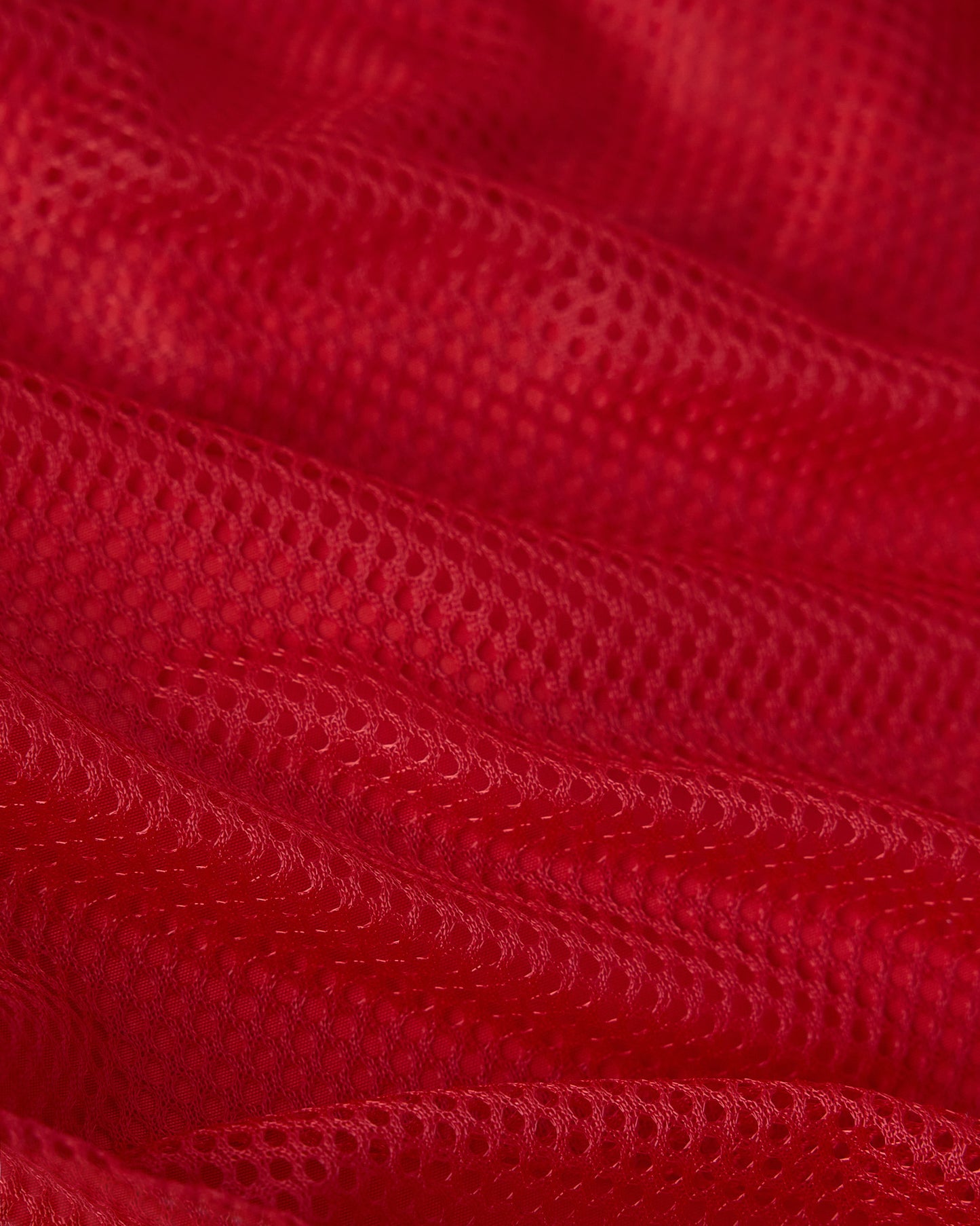 Red swim short fabric with quilted texture and visible stitching details.