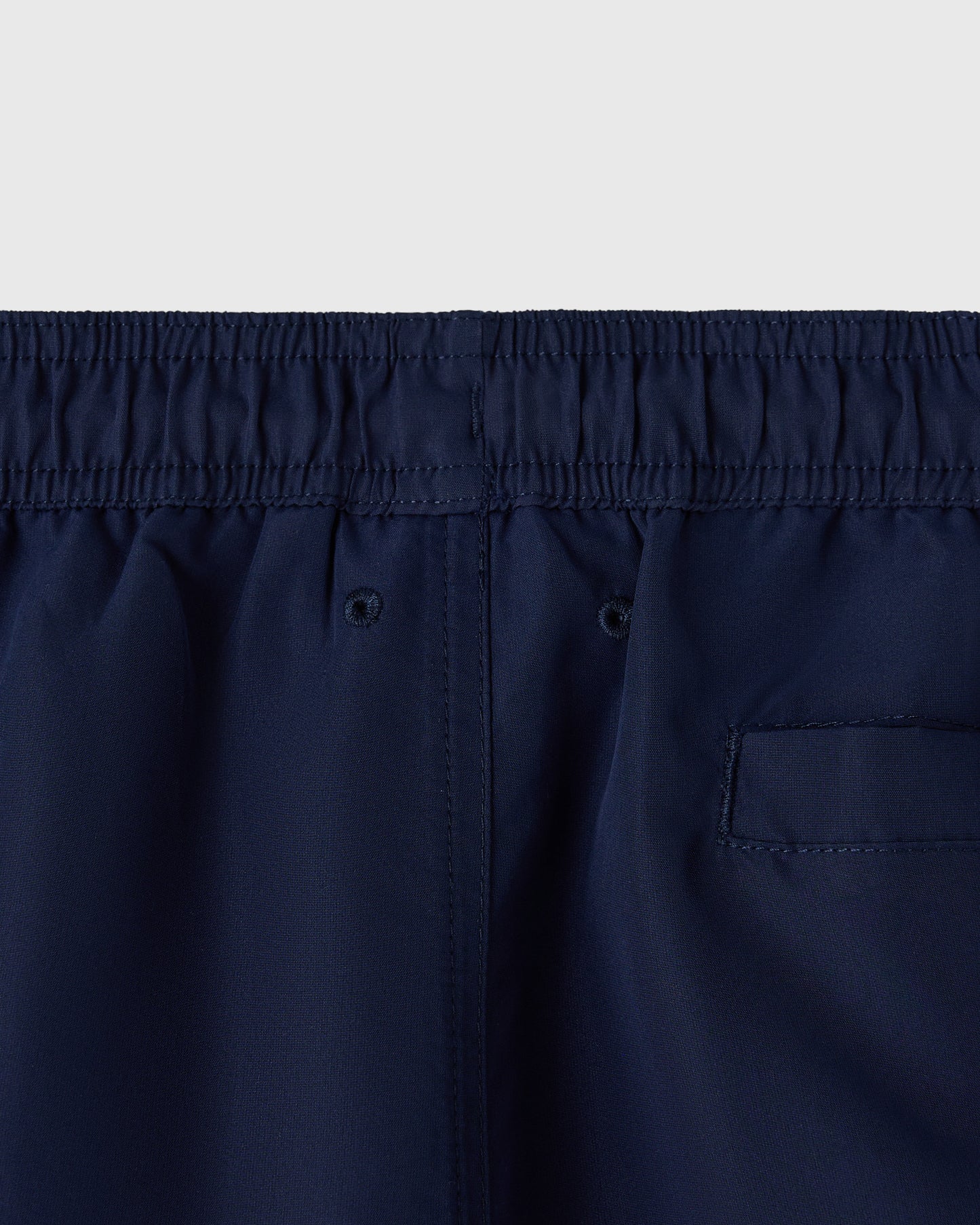 Navy swim shorts with elasticated waistband, drawstring, and rear patch pocket.
