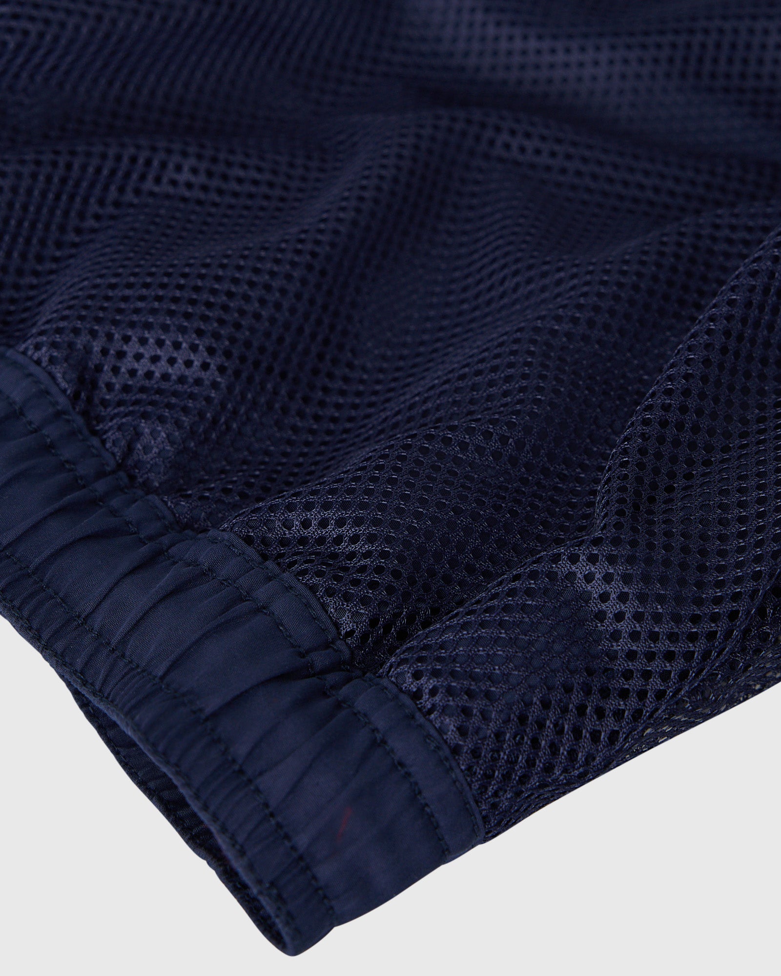 Navy swim short with textured mesh fabric and elastic waistband detail.