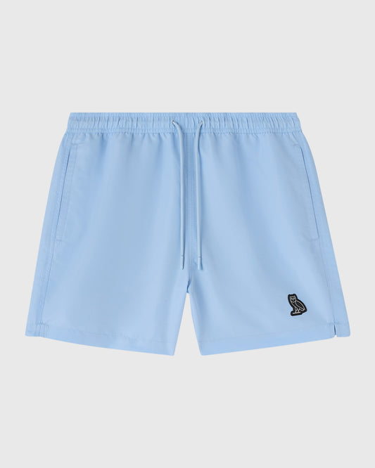 Light blue swim shorts with drawstring waist, side pockets, and small embroidered logo on thigh.