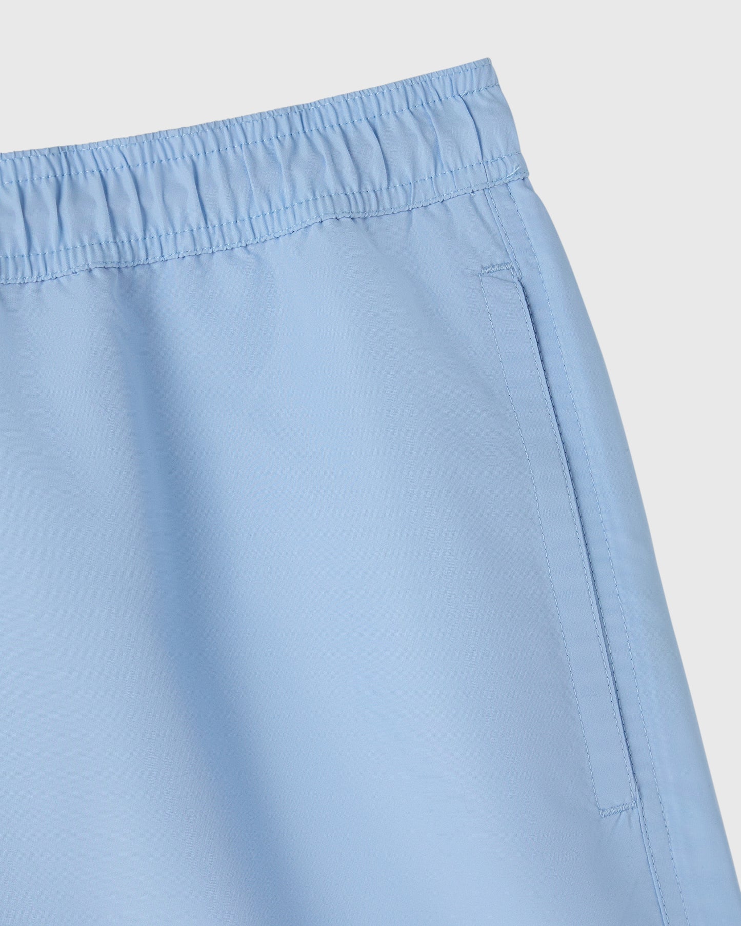 Light blue swim short with elastic waistband and side pocket detail.