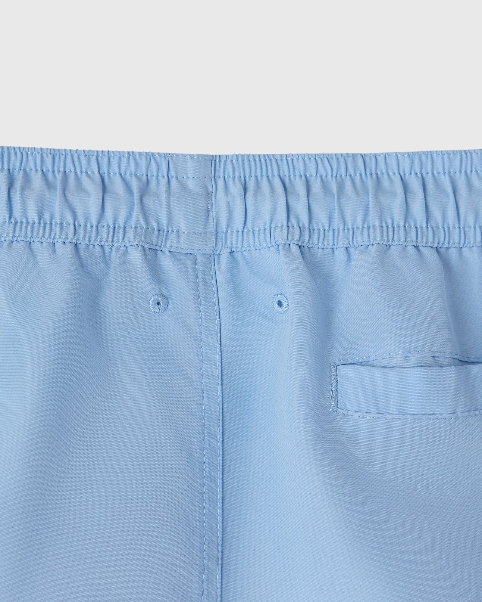 Light blue swim shorts with elastic waistband, drawstring, and back pocket detail.