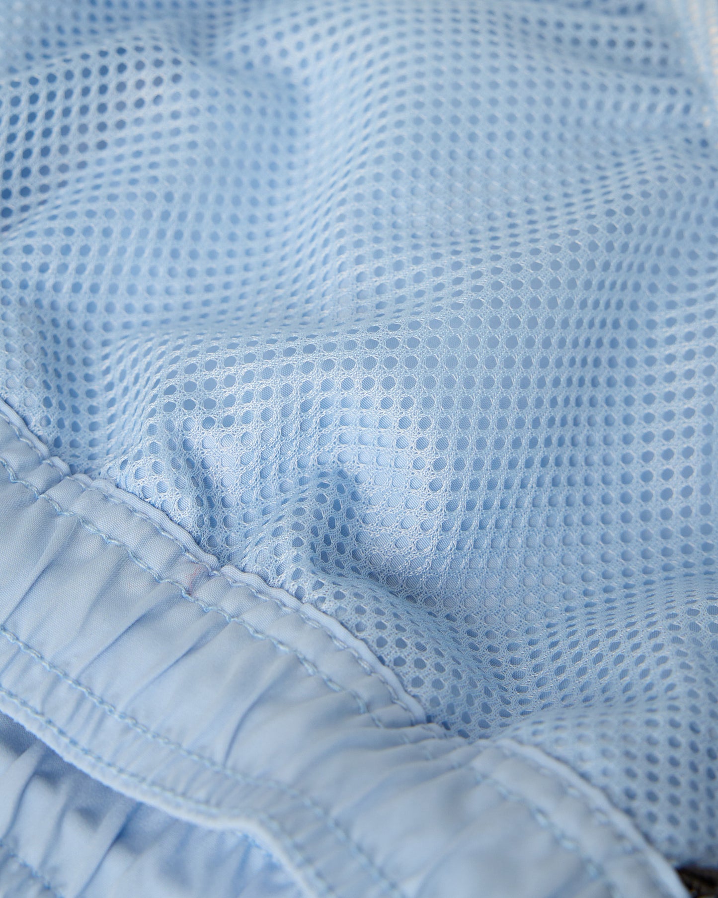Light blue swim short with mesh fabric texture and elastic waistband detail.