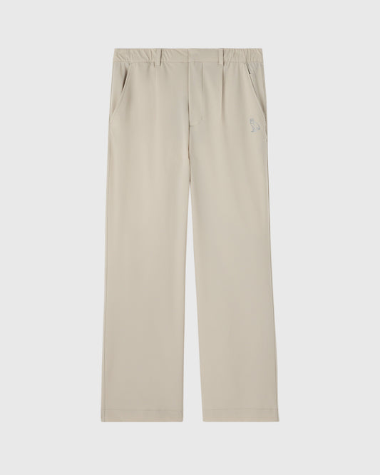 Sandstone stretch nylon chino pants with front pleats, side pockets, and small logo detail on thigh.