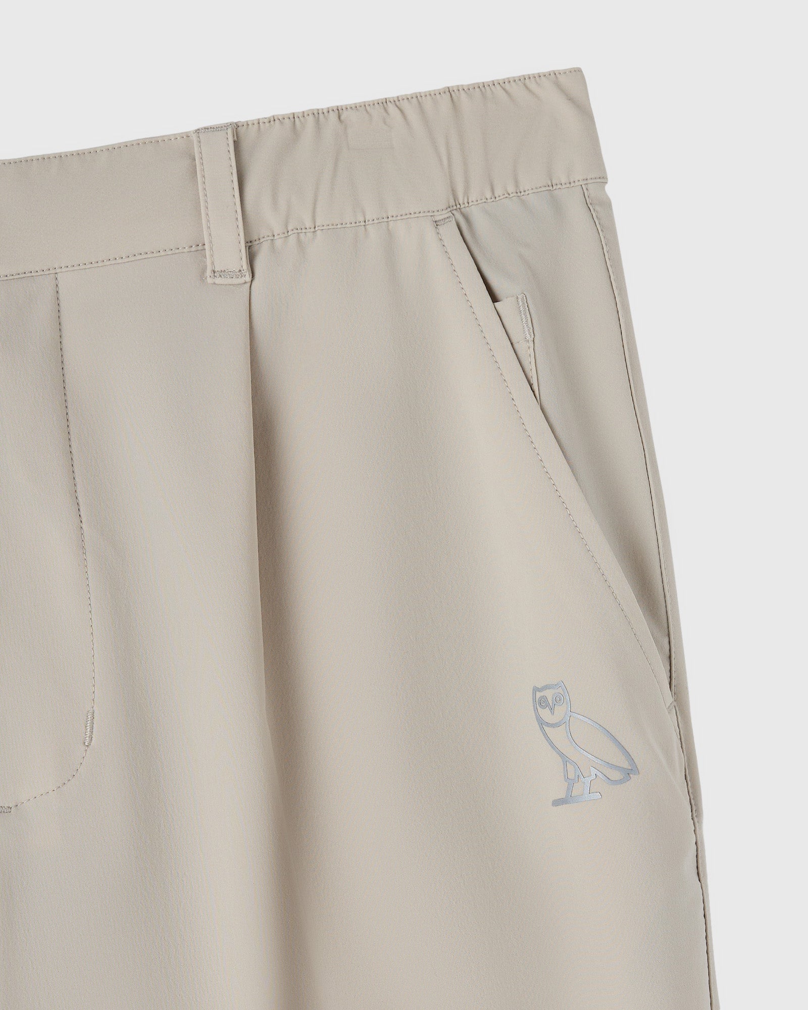 Sandstone stretch nylon chino pants with flat front, side pockets, and small bird logo embroidered on thigh.