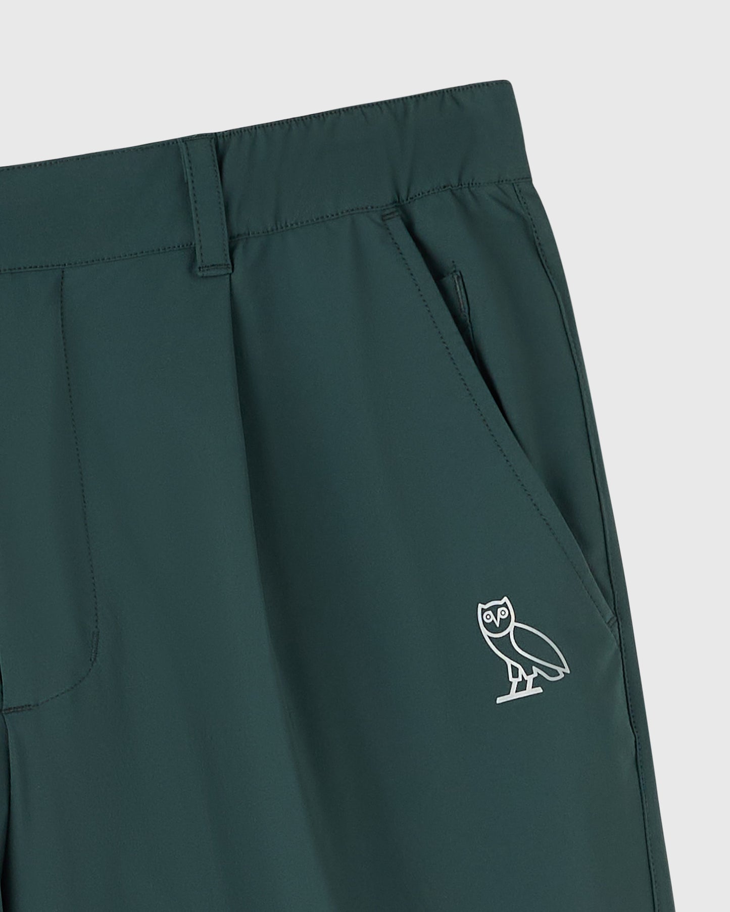 Midnight green stretch nylon chino pants with front pockets and white owl logo on thigh.