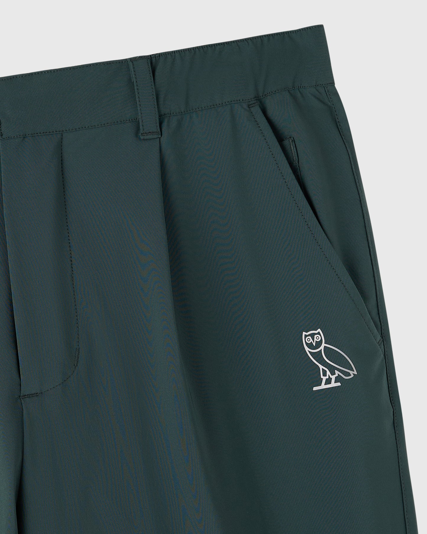 Midnight green stretch nylon chino pants with front pockets and white owl logo embroidered on thigh.