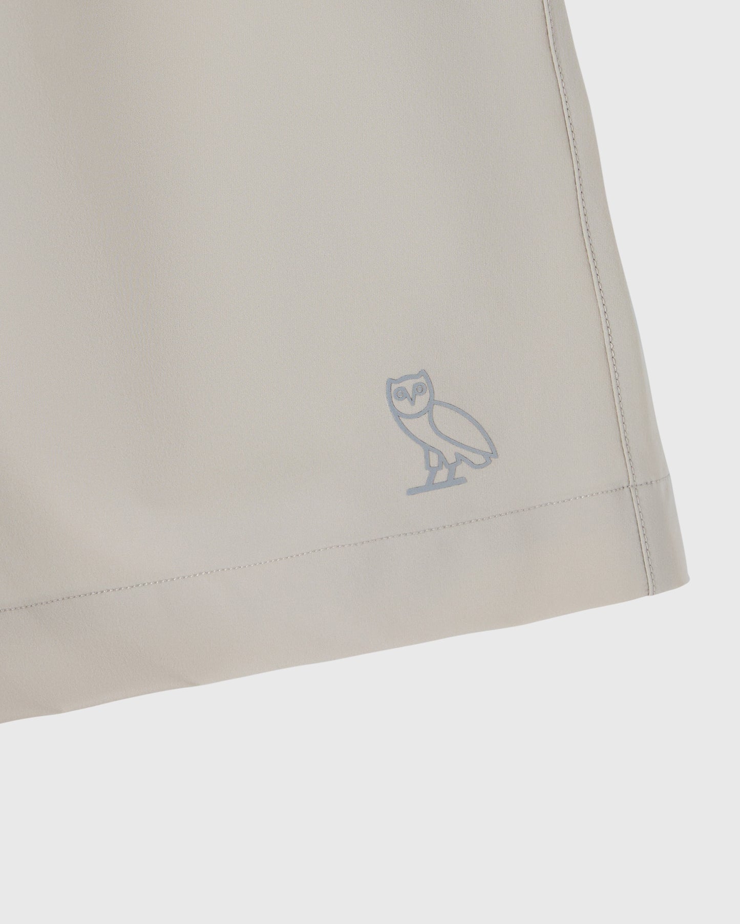Sandstone golf short with embroidered owl logo on the thigh and stitched side seam detail.