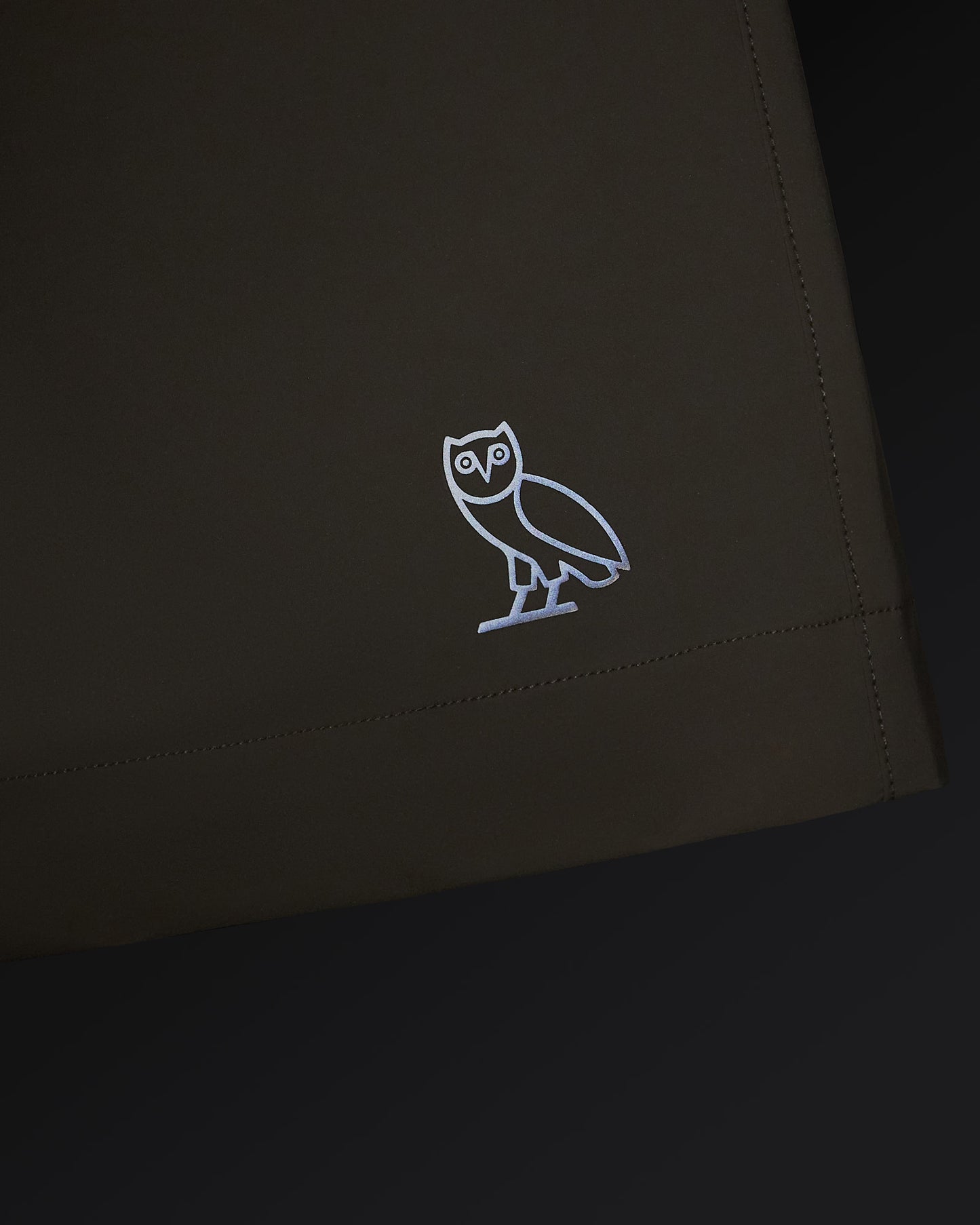 Sandstone golf short with white owl logo embroidered on thigh and stitched seam detail.