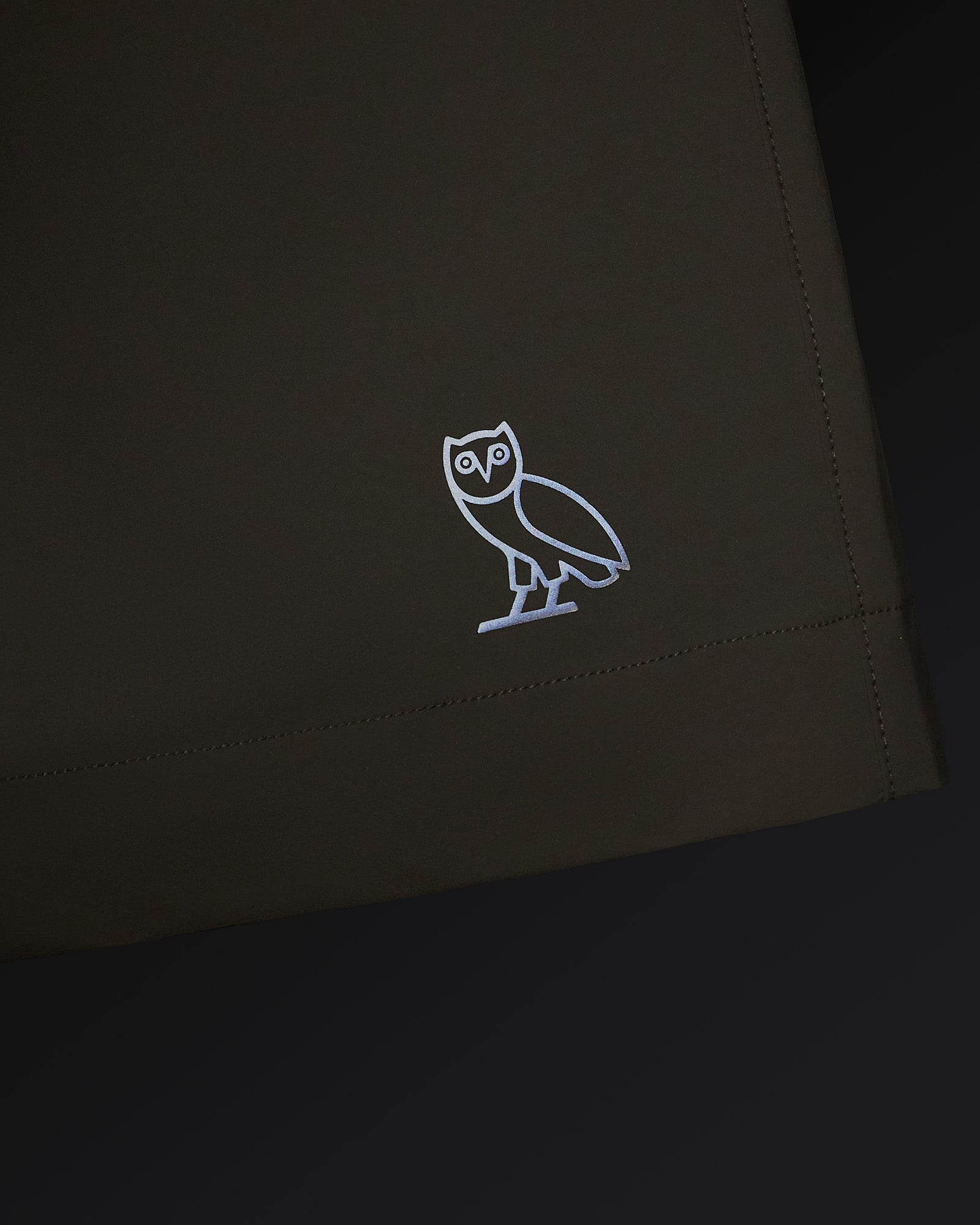 Sandstone golf short with white owl logo embroidered on thigh and stitched seam detail.