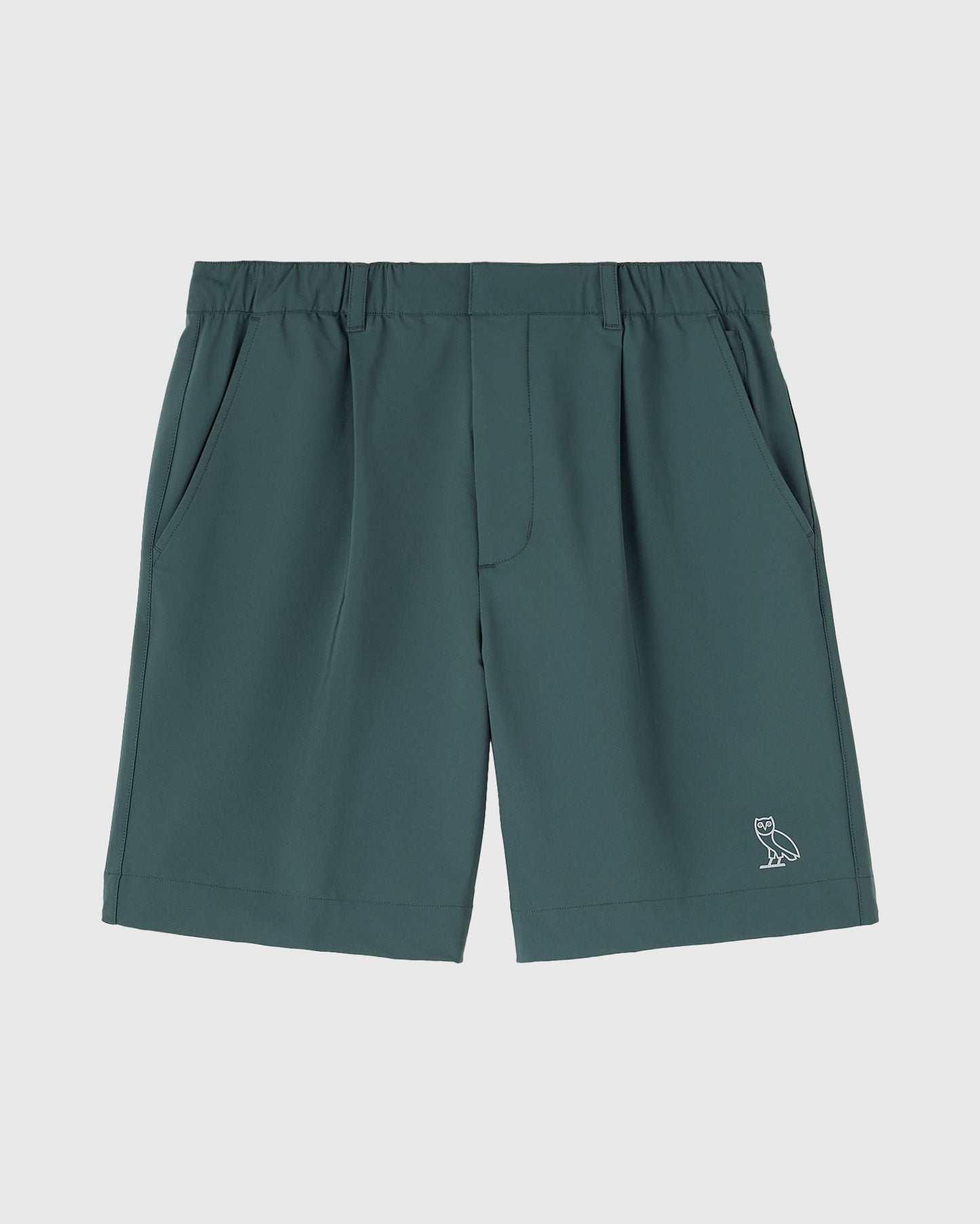 Midnight green golf shorts with pleated front pockets, elastic waistband, and small owl logo on lower leg.