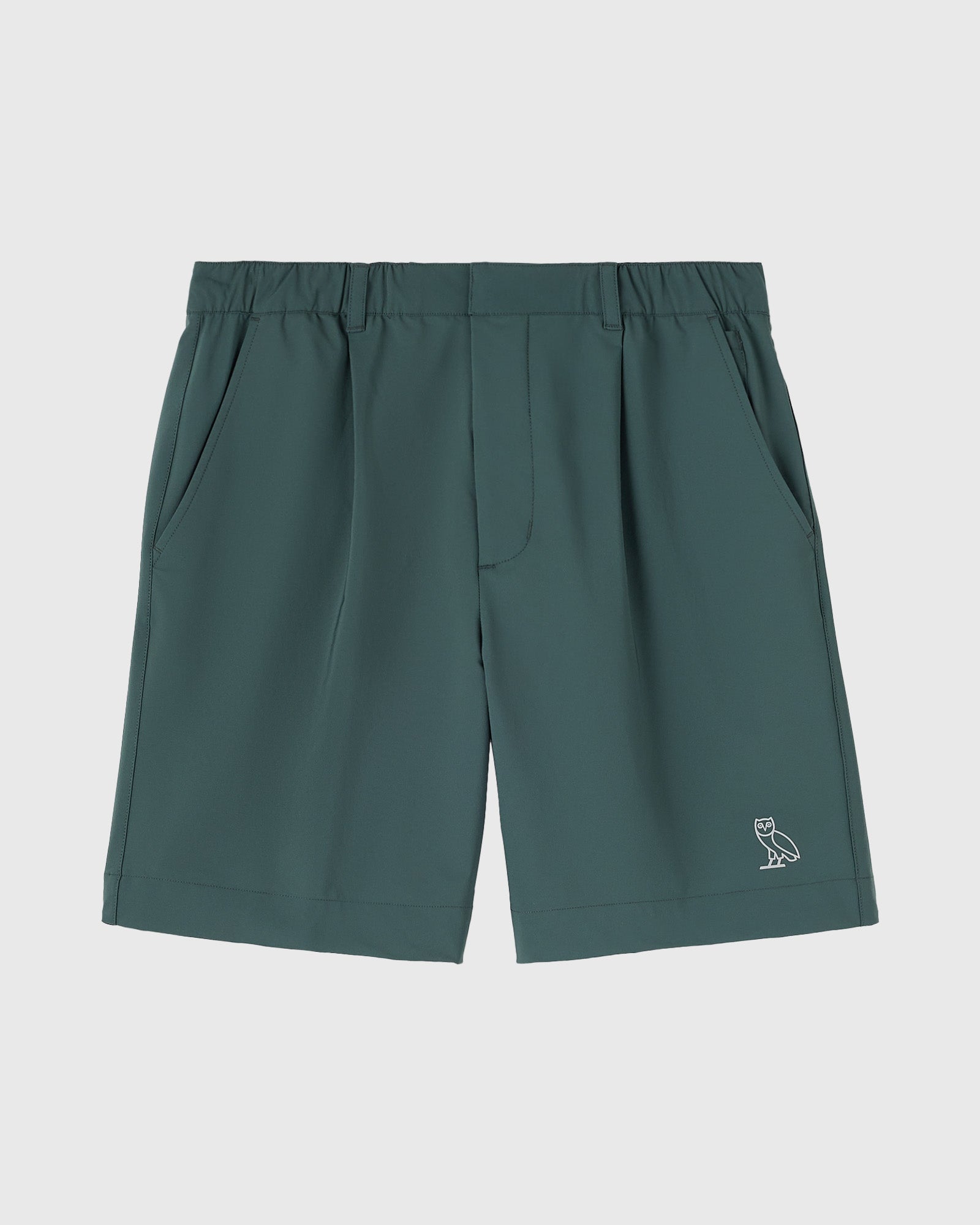 Midnight green golf shorts with pleated front pockets, elastic waistband, and small owl logo on lower leg.