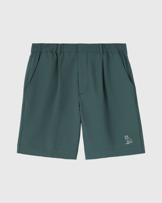 Midnight green golf shorts with pleated front pockets, elastic waistband, and small owl logo on lower leg.