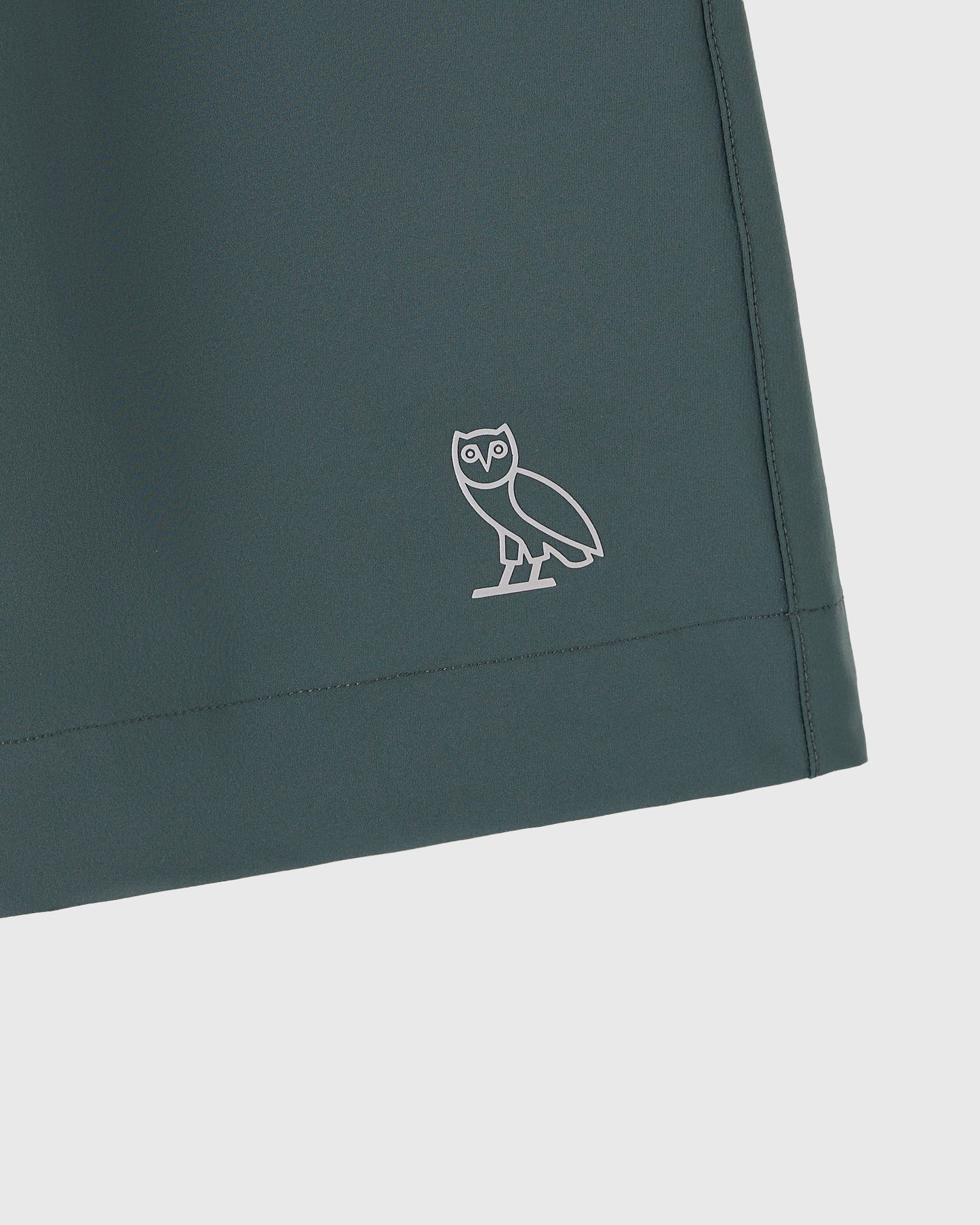 Midnight green golf short with white owl embroidered logo on thigh.