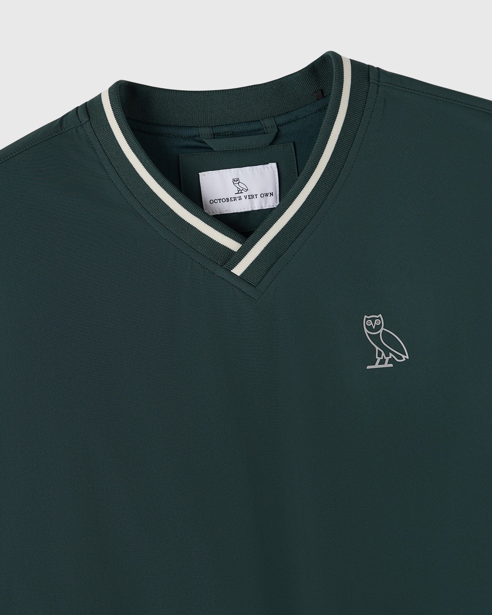 Midnight green V-neck pullover with white striping at neckline and small owl logo on chest.