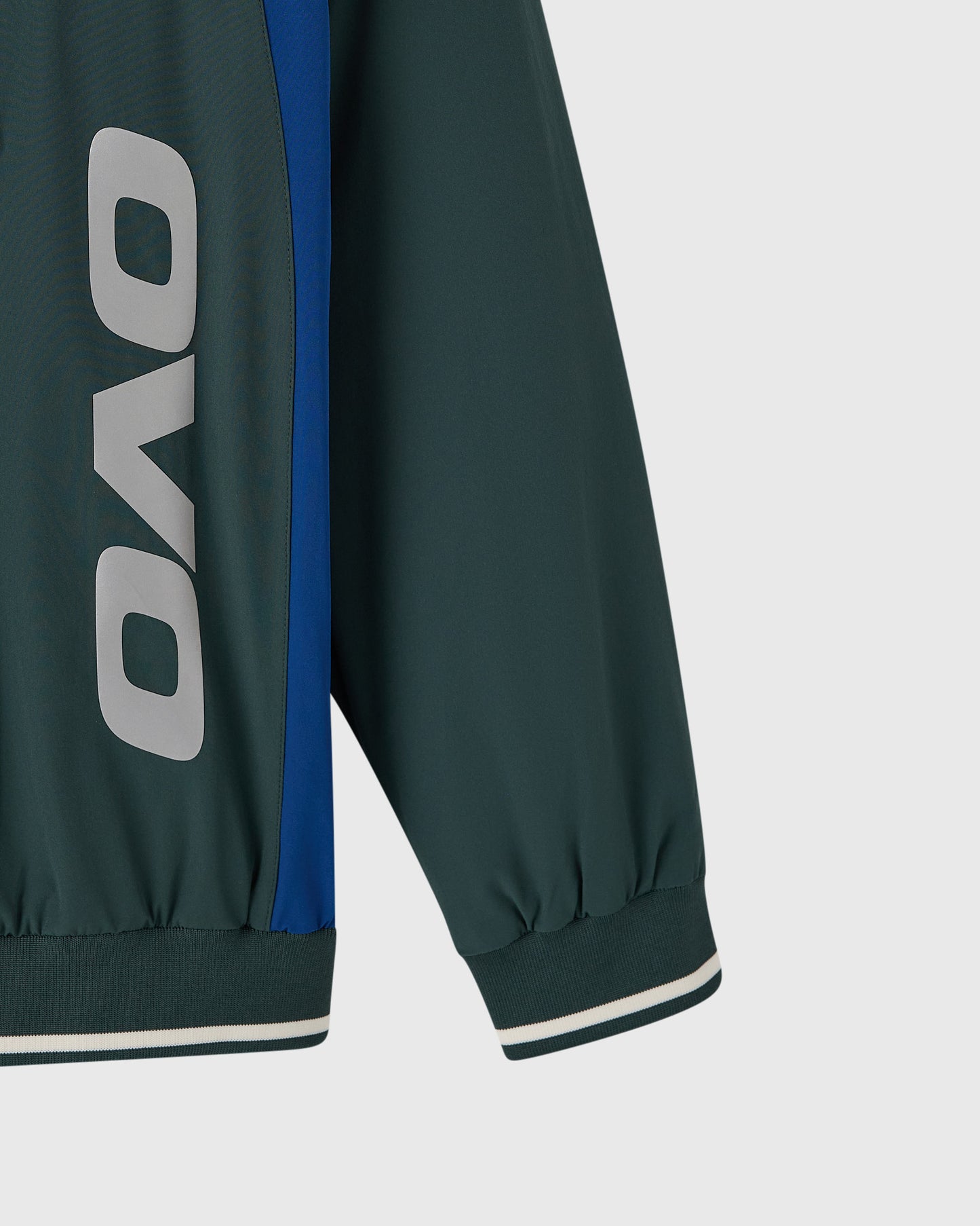 Midnight green pullover with OVO logo, blue stripe detail, and ribbed cuffs with contrast trim.