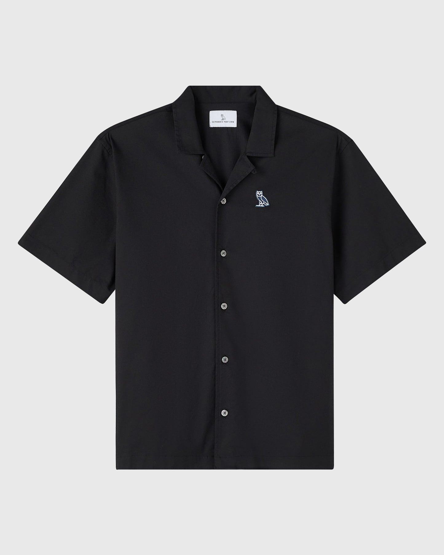 Black camp shirt with short sleeves, collared neckline, front button closure, and small owl emblem on chest.