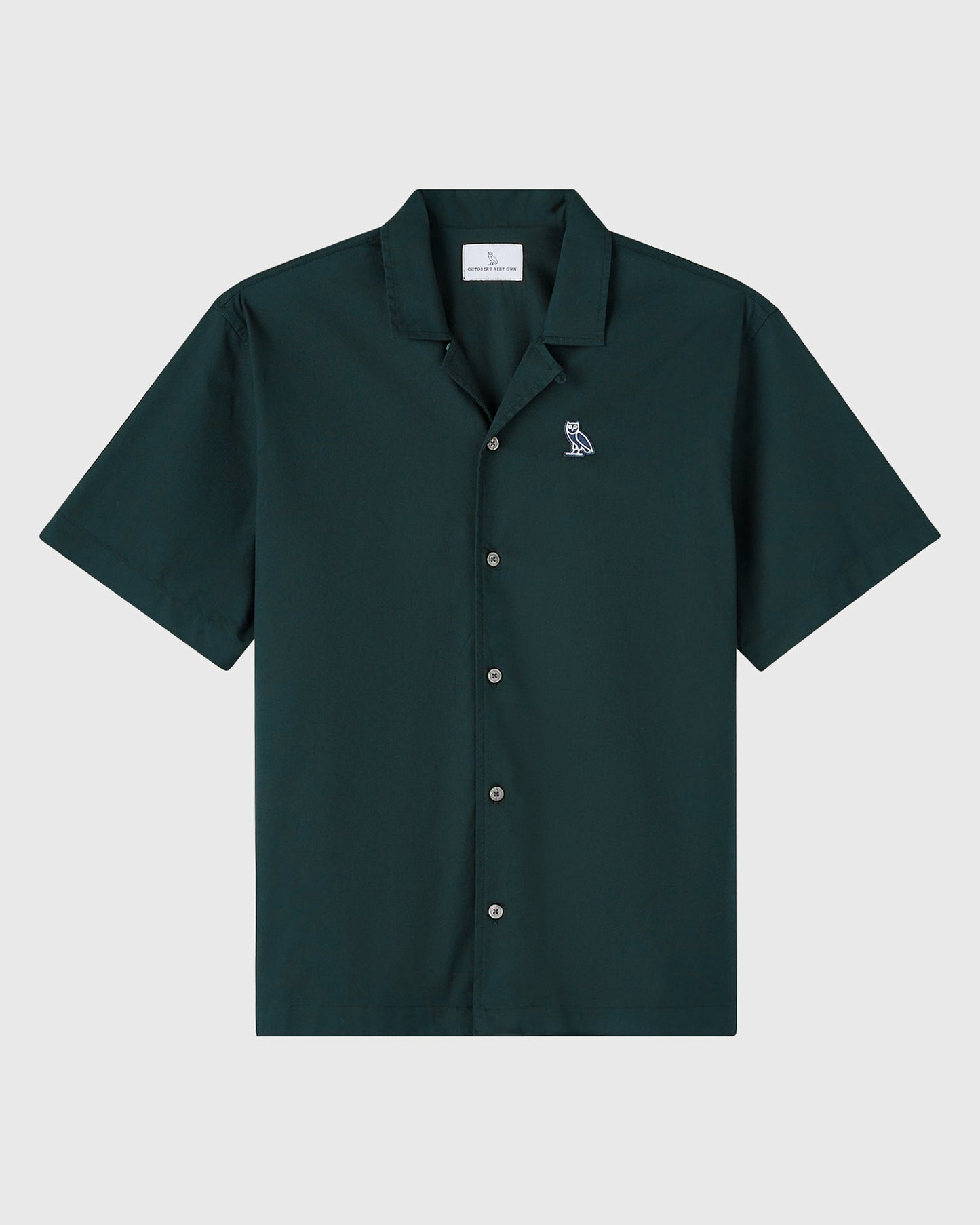 Midnight green camp shirt with short sleeves, collar, and small owl embroidered on chest.