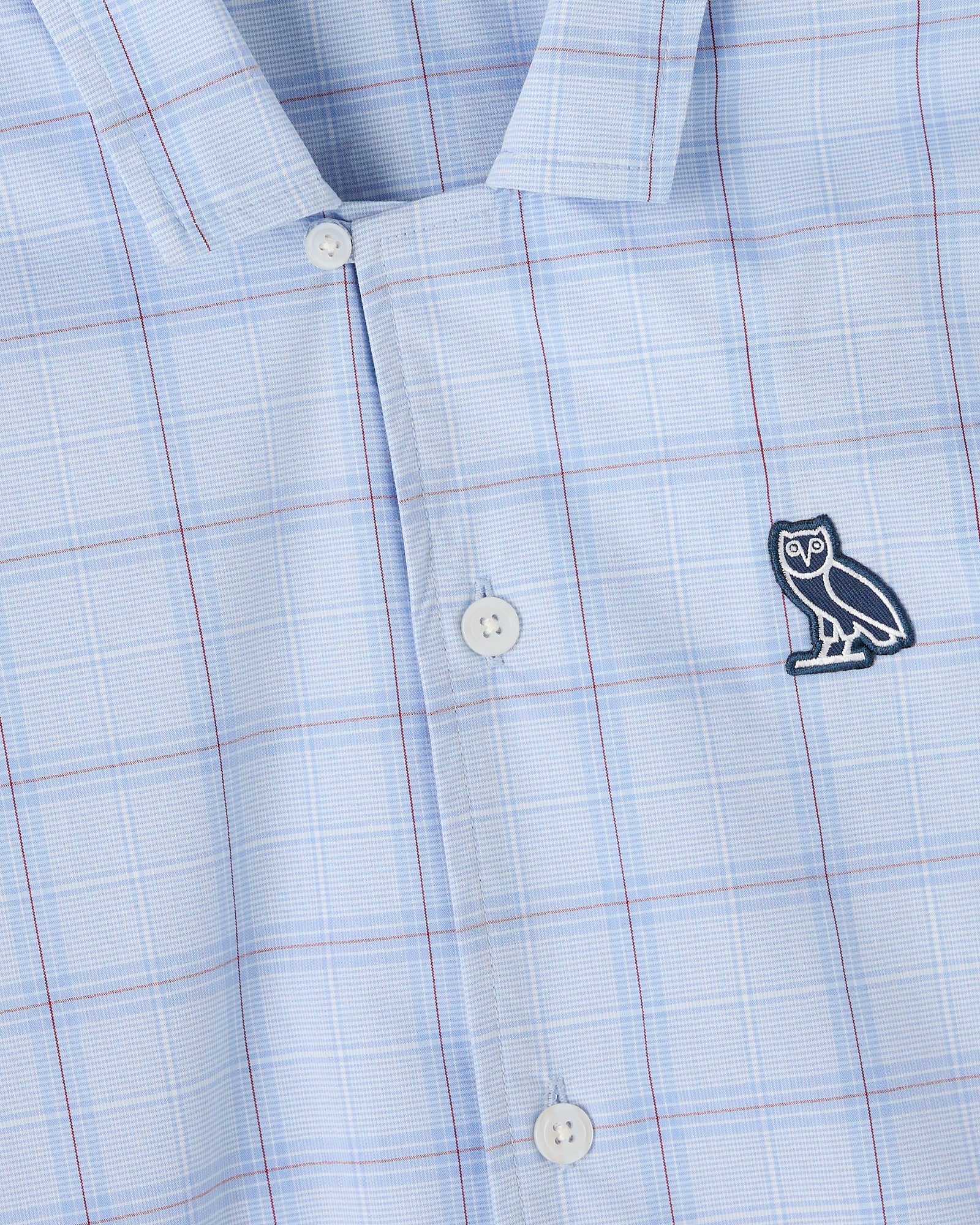 Light blue camp shirt with red and white grid pattern, white buttons, and embroidered owl logo on chest.