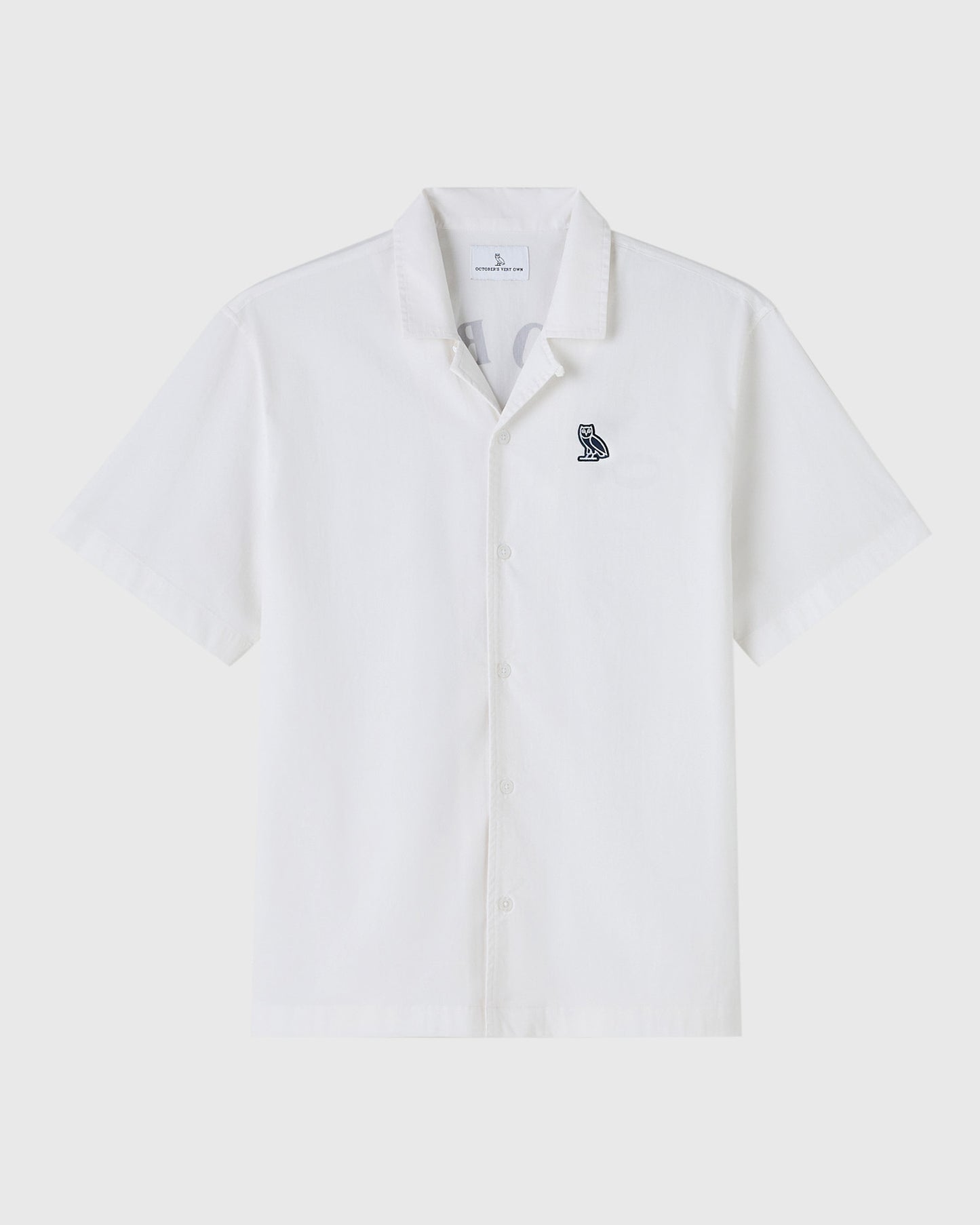 White short-sleeve camp shirt with small embroidered owl logo on chest and button front closure.