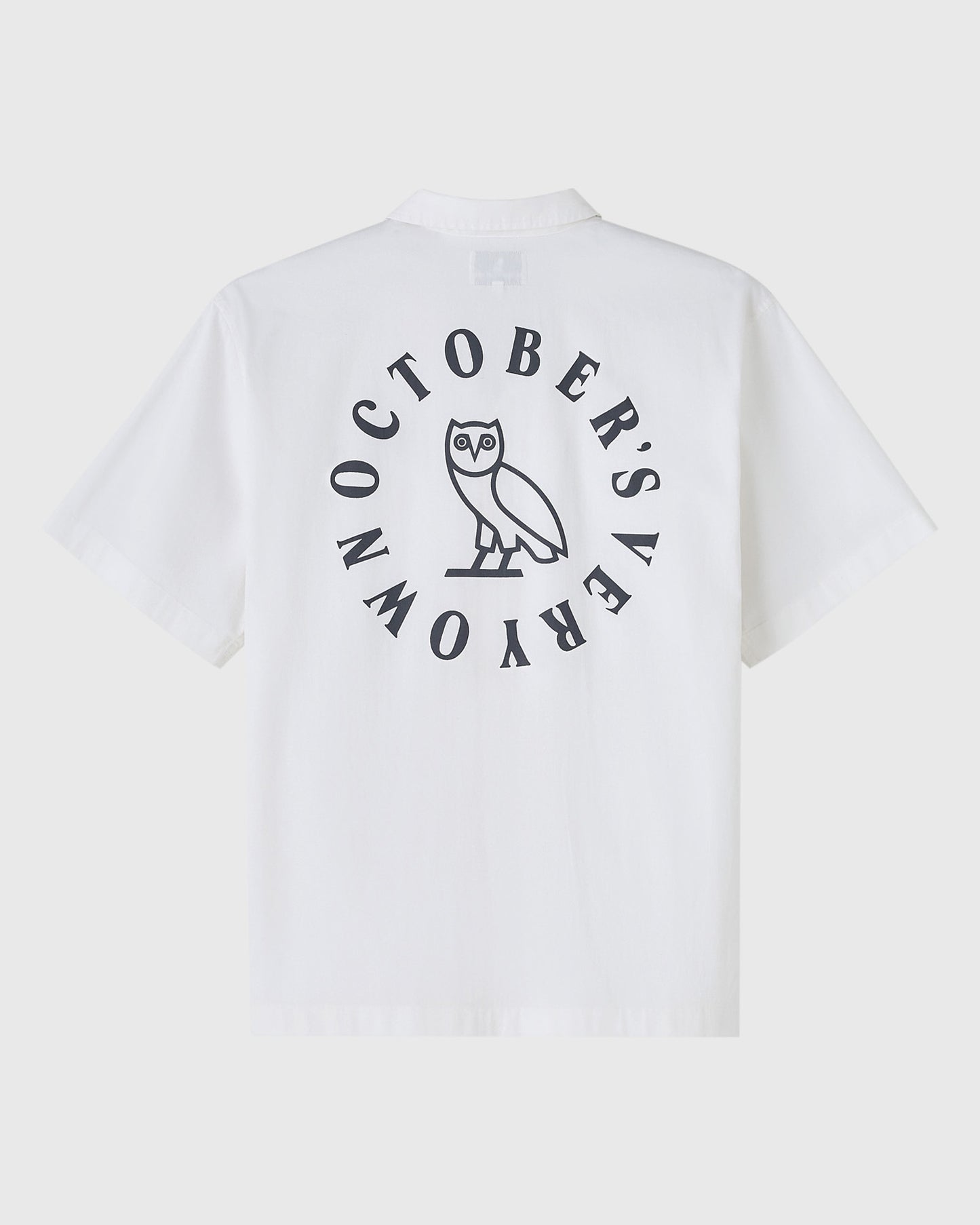 White camp shirt with circular back graphic featuring an owl and text reading "October's Rara" in dark print.