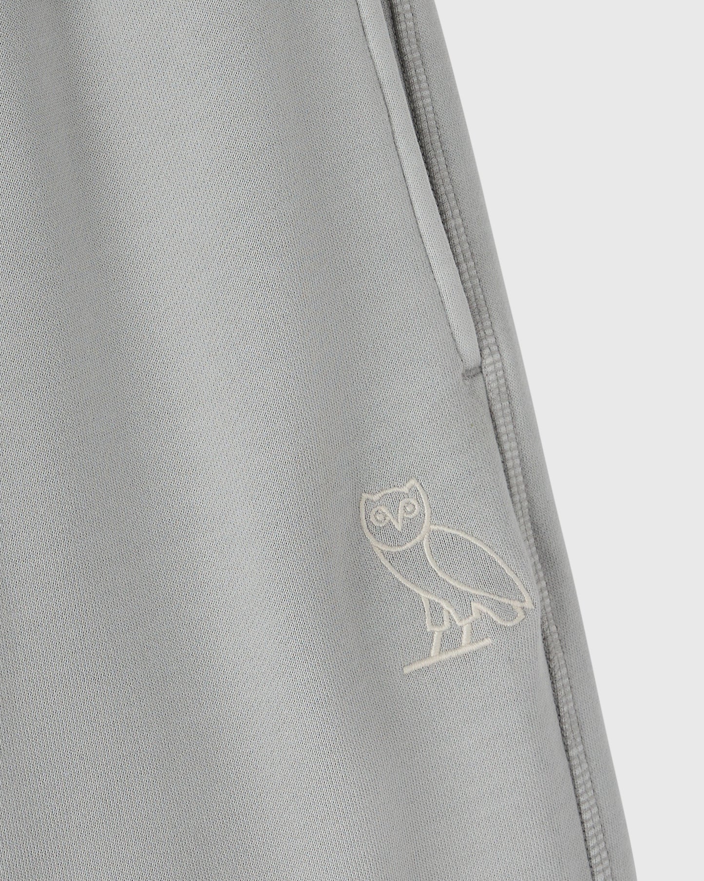 Gray sweatpant with embroidered owl logo and side seam detail.