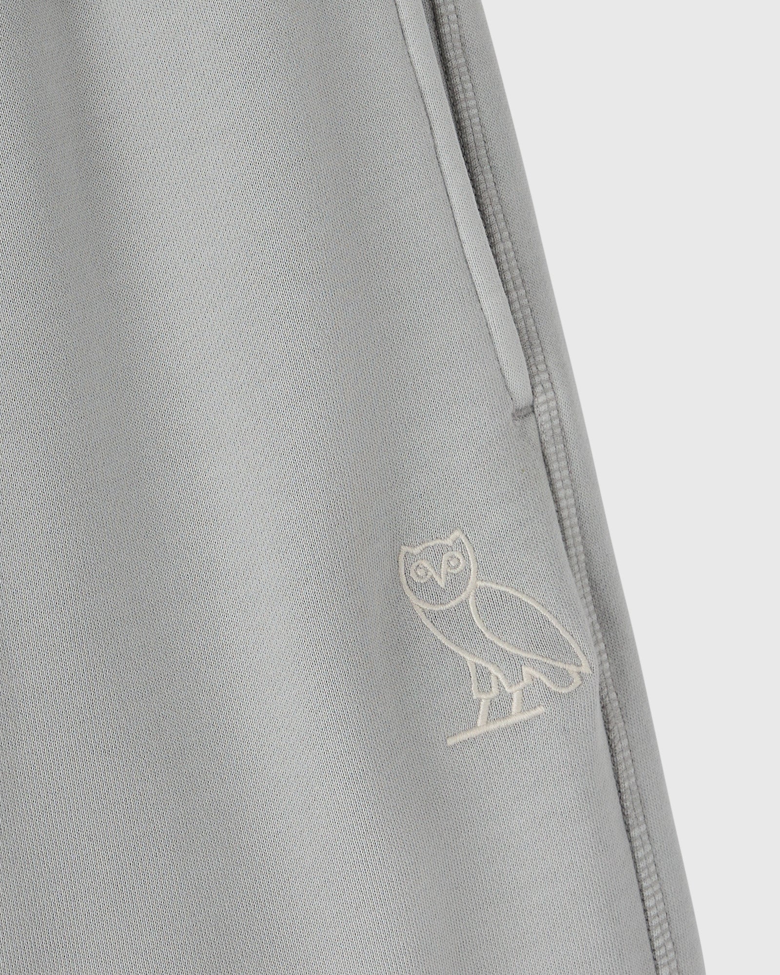 Gray sweatpant with embroidered owl logo and side seam detail.