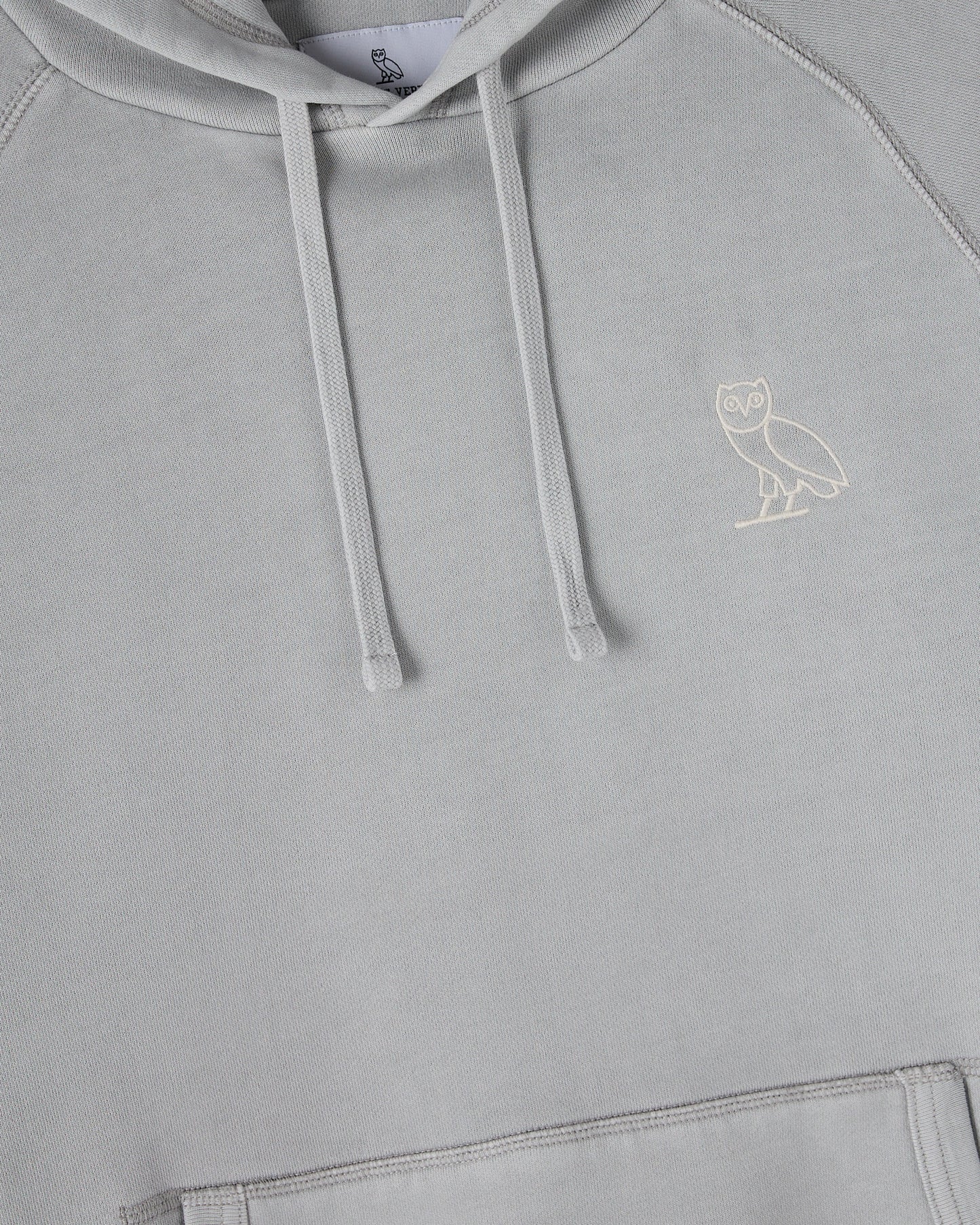 Gray raglan hoodie with white drawstrings and small owl embroidery on chest.