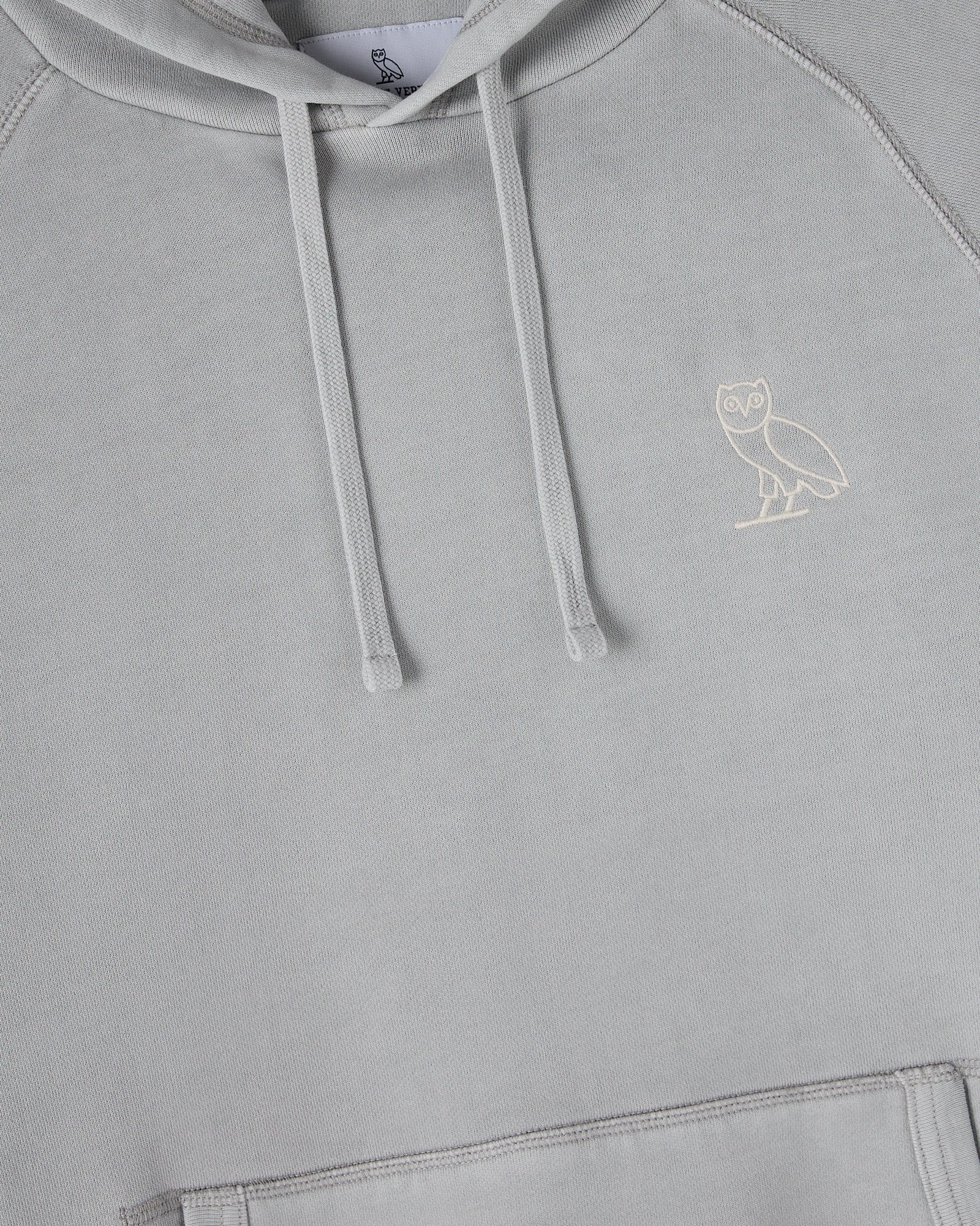 Gray raglan hoodie with white drawstrings and small owl embroidery on chest.
