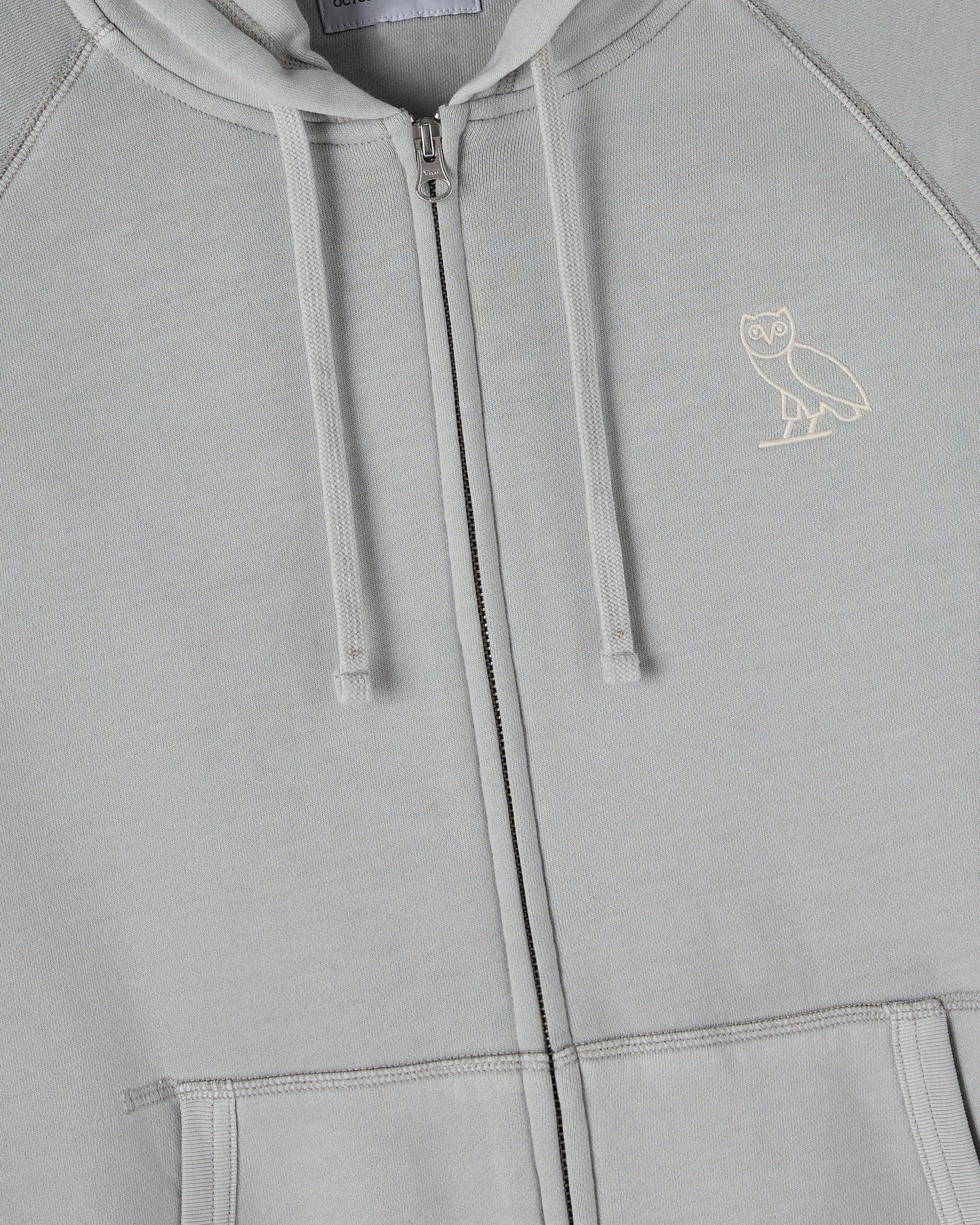 Gray raglan full-zip hoodie with white drawstrings and small owl emblem on chest.